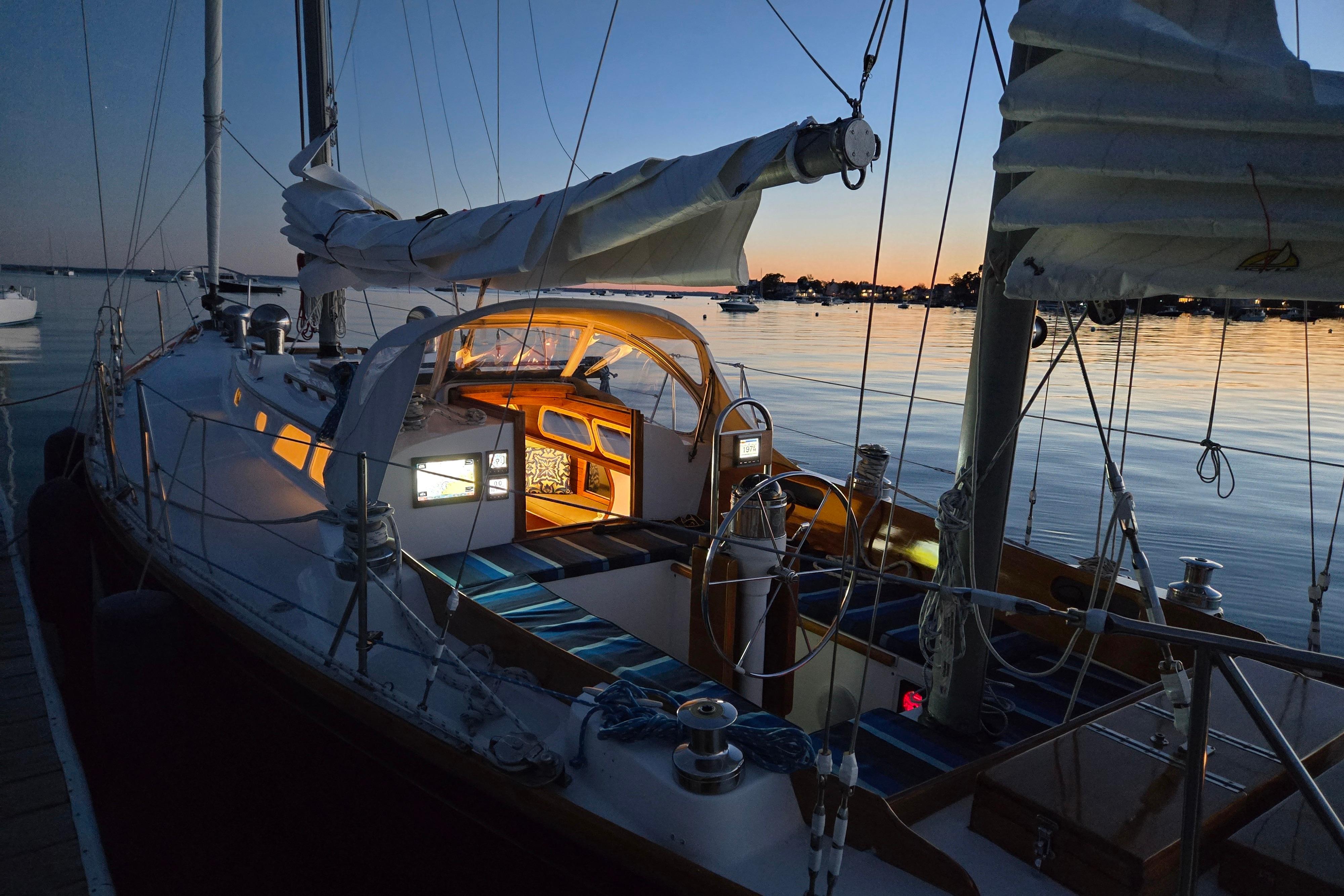 Hinckley Bermuda 40 sailboat at sunset, docked with illuminated cabin, 1970 model.