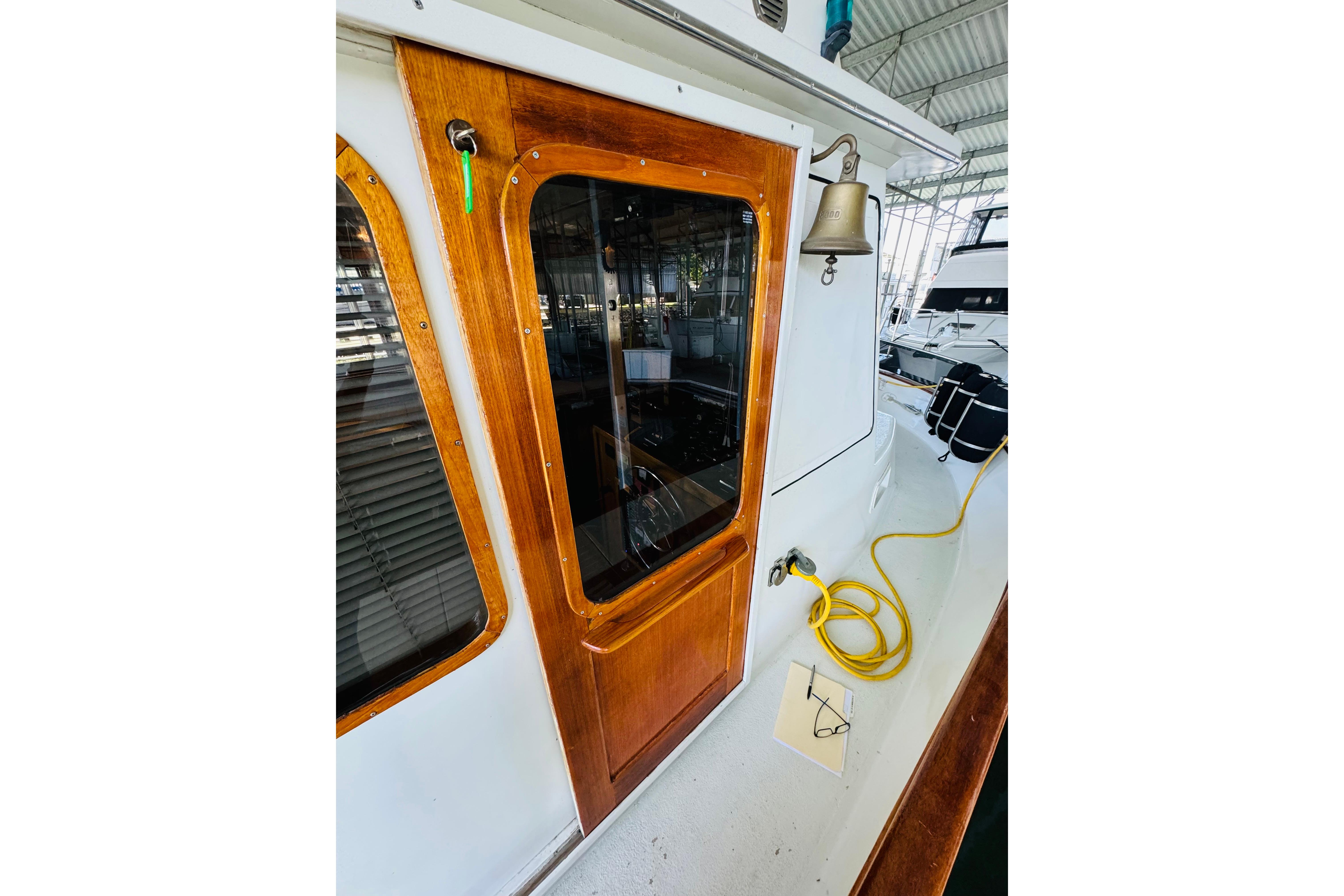 1978 Californian 42 LRC boat with wooden door, bell, and yellow hose on deck.