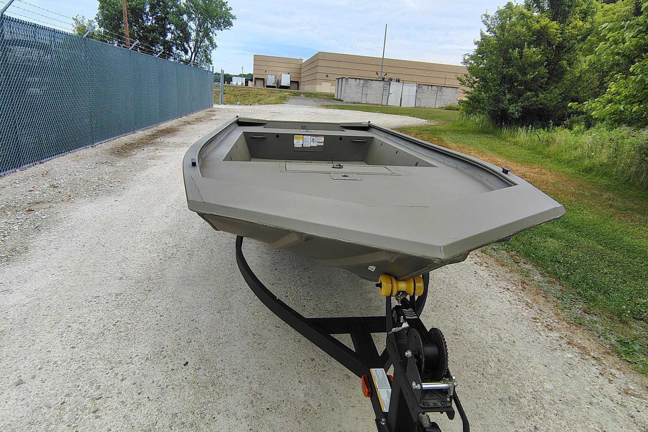 2026 Tracker Grizzly 1754 Utility boat on trailer, parked on gravel path.