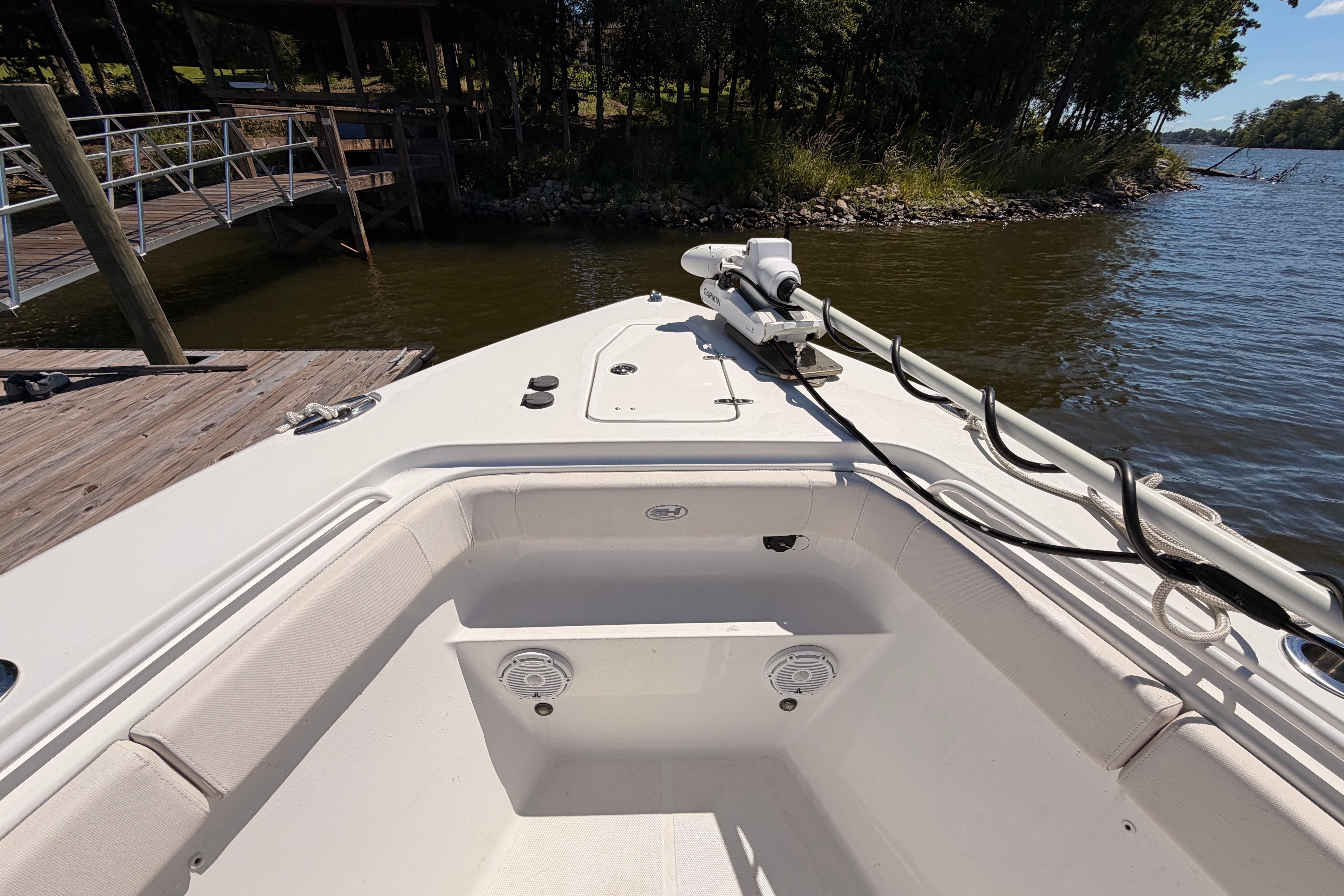 2024 Sea Hunt Gamefish 27 Coffin Box boat docked by a serene lakeside.