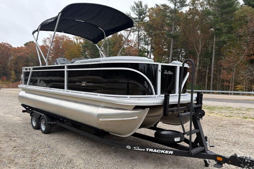 2026 Sun Tracker Party Barge 22 RF XP3 pontoon boat on trailer, surrounded by trees.