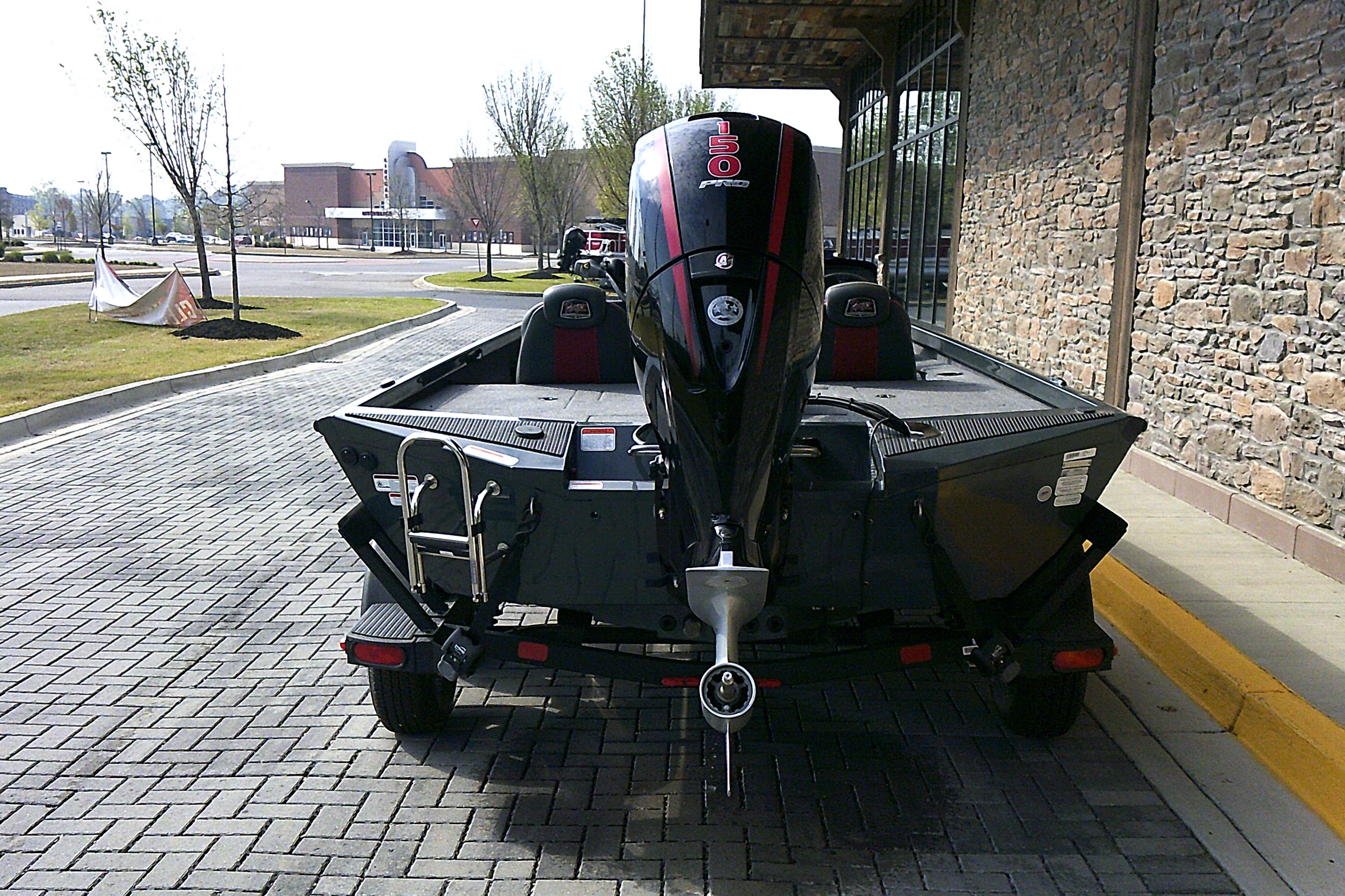 2025 Ranger RT198P boat with powerful outboard motor, parked on brick pavement.