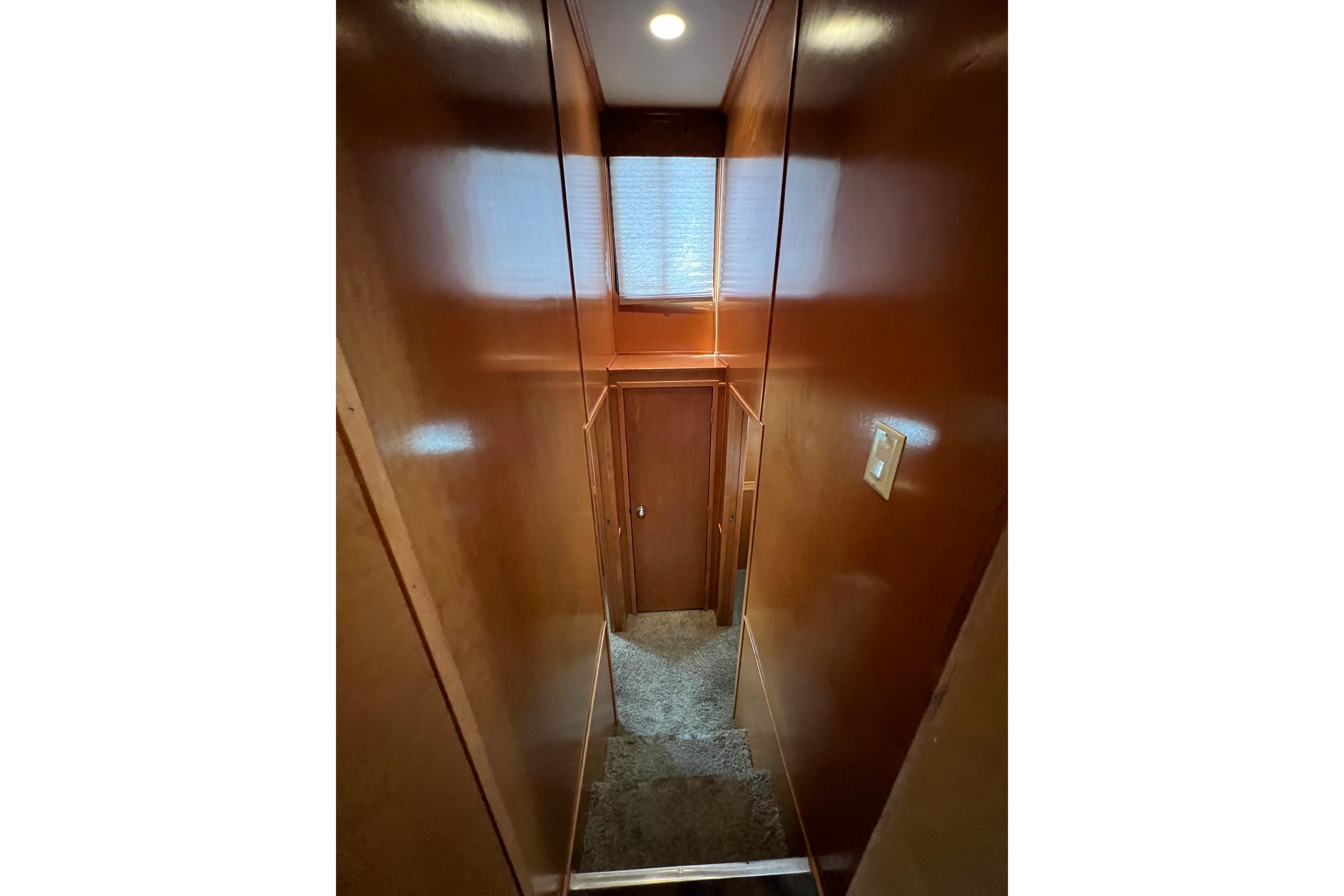 Narrow hallway inside 2013 Destination Yacht Lotta Yachta with wooden walls and carpeted stairs.