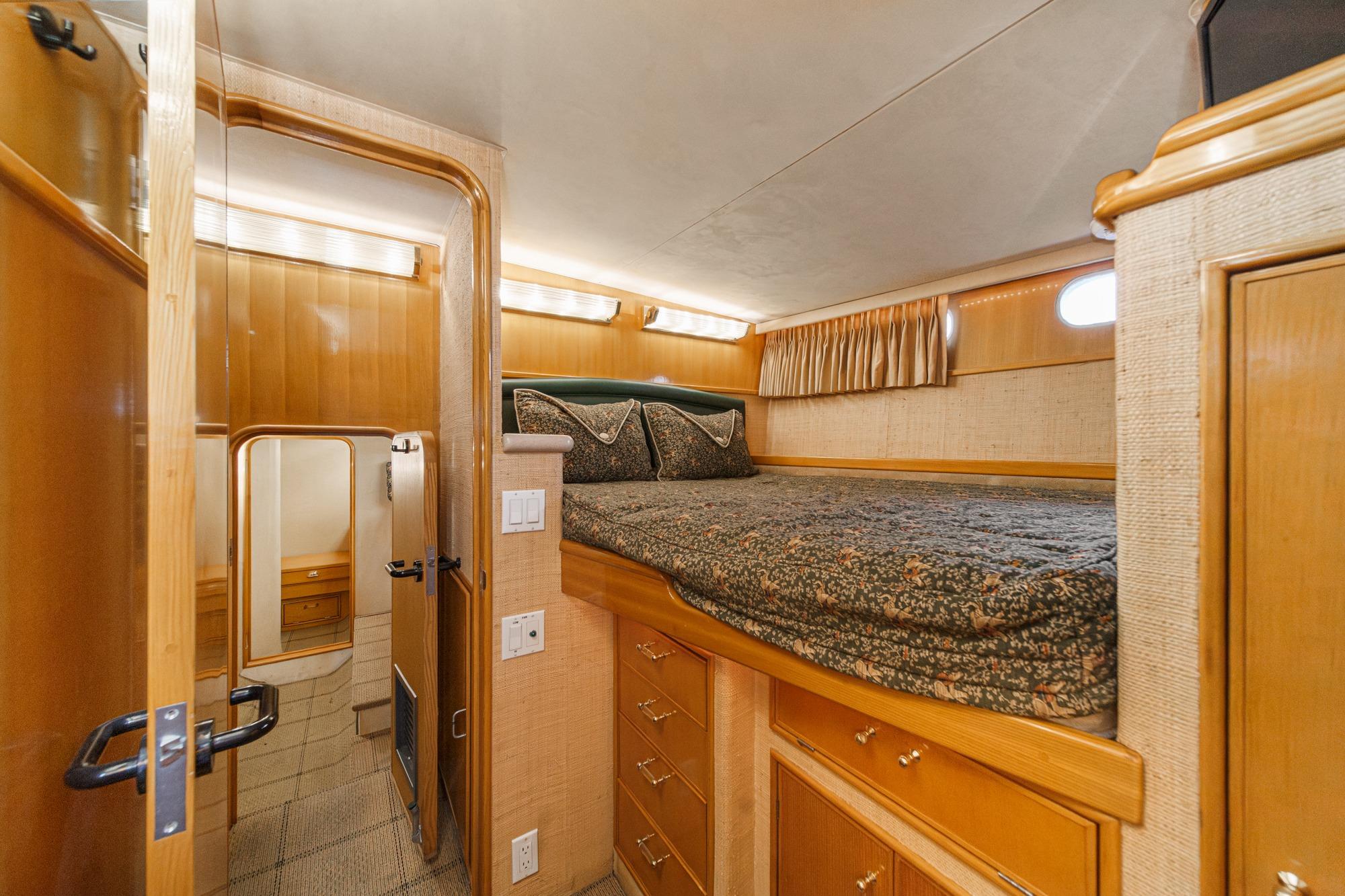 Cozy cabin interior of 1990 Seaton Long Range Cruiser with wooden furnishings and bed.