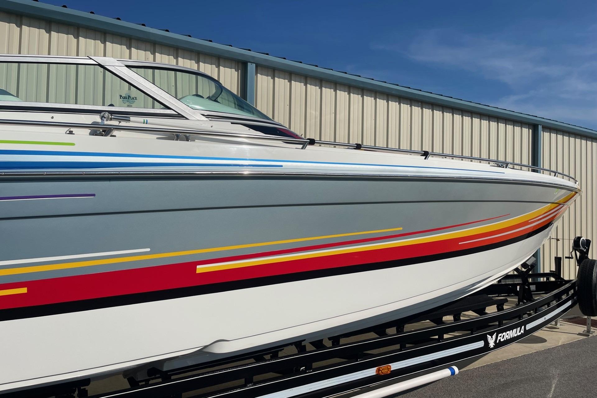 2004 Formula 382 FASTech boat with colorful stripes on a trailer, parked outdoors.