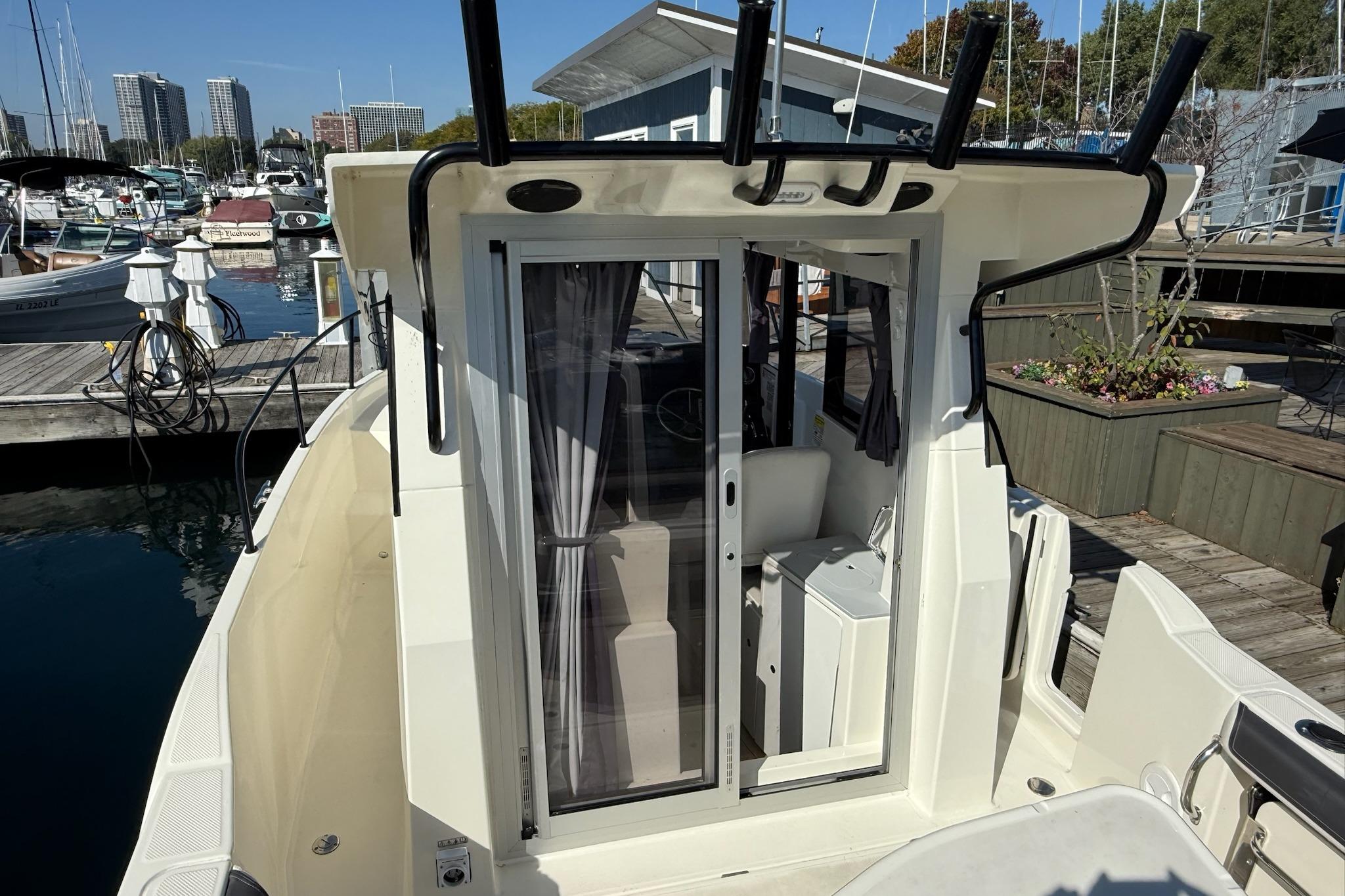 2024 Bayliner Trophy T25 Pilothouse docked at marina, showcasing sliding door and pilothouse interior.