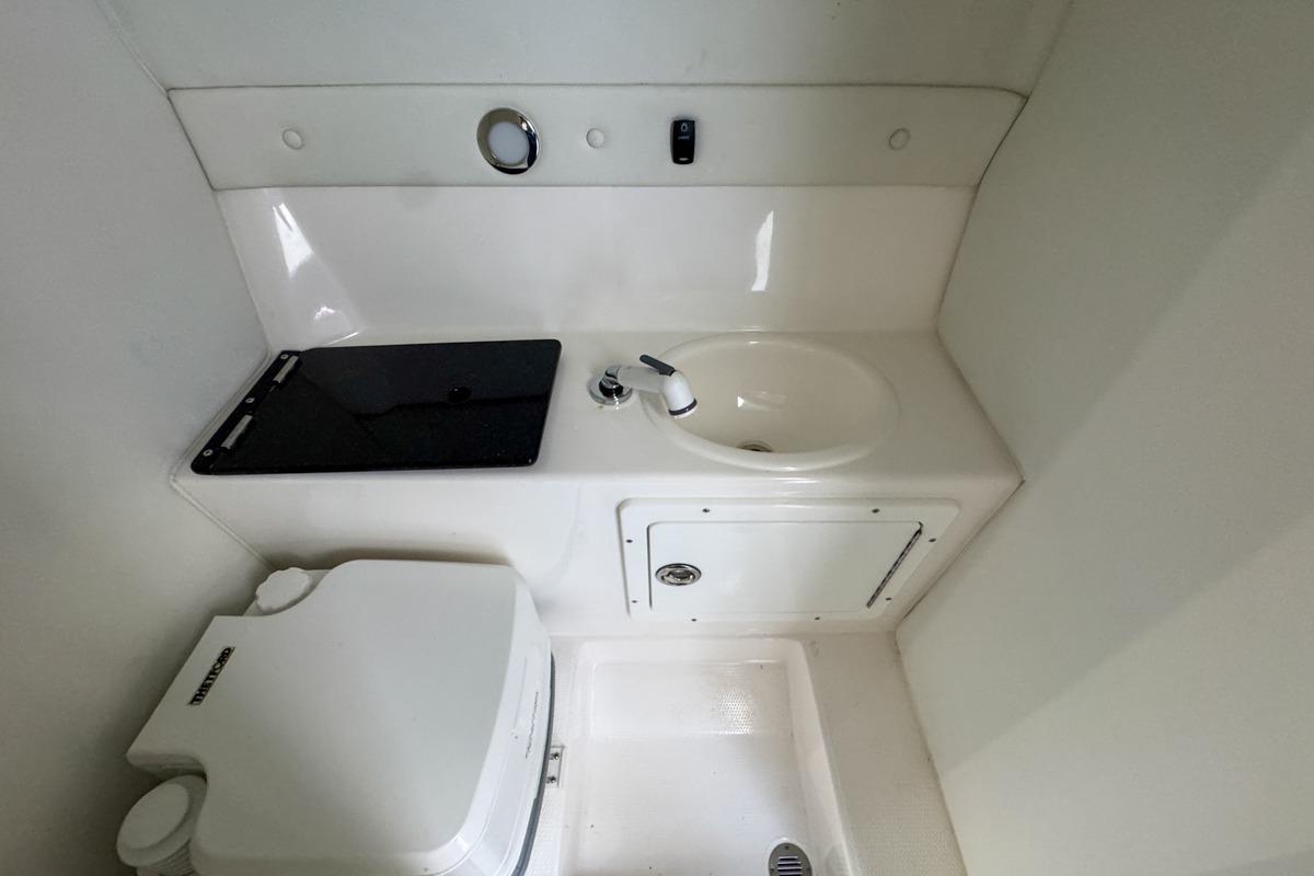 Compact bathroom in 2022 Velocity 290sc boat with sink and toilet.