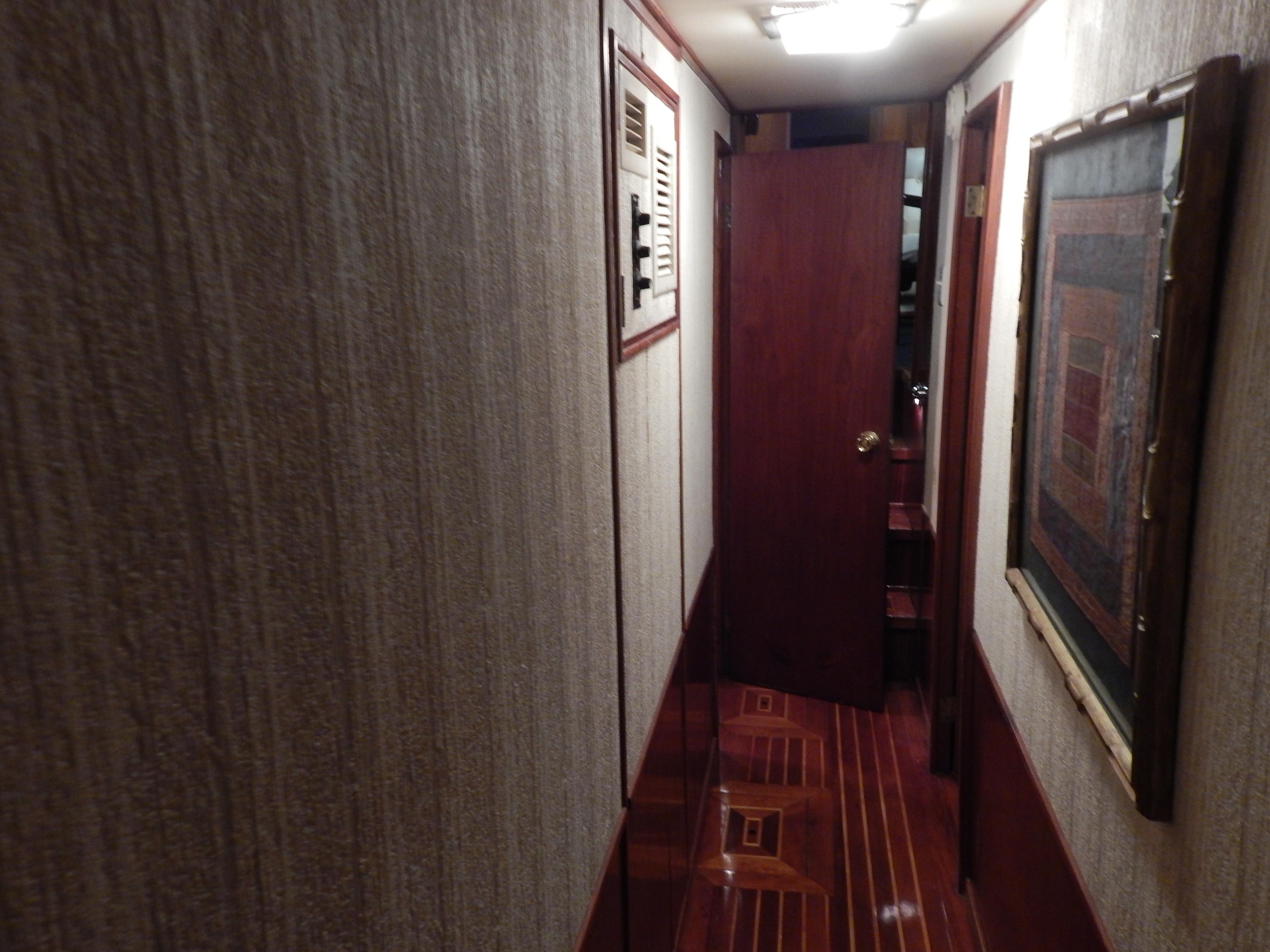 1974 Pacemaker Cockpit Motoryacht interior hallway with wood paneling and framed artwork.