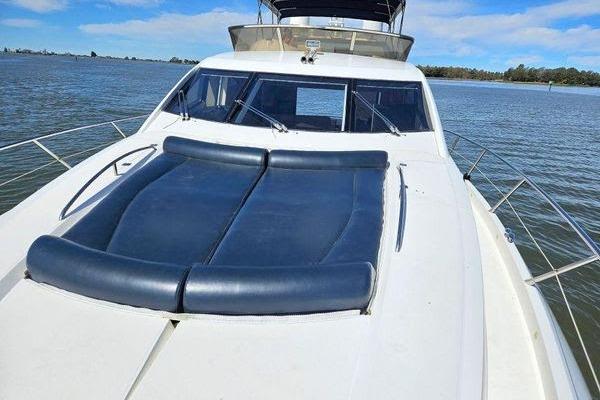 2005 Sunseeker Manhattan 66 yacht with blue sunbed on deck, cruising on calm waters.