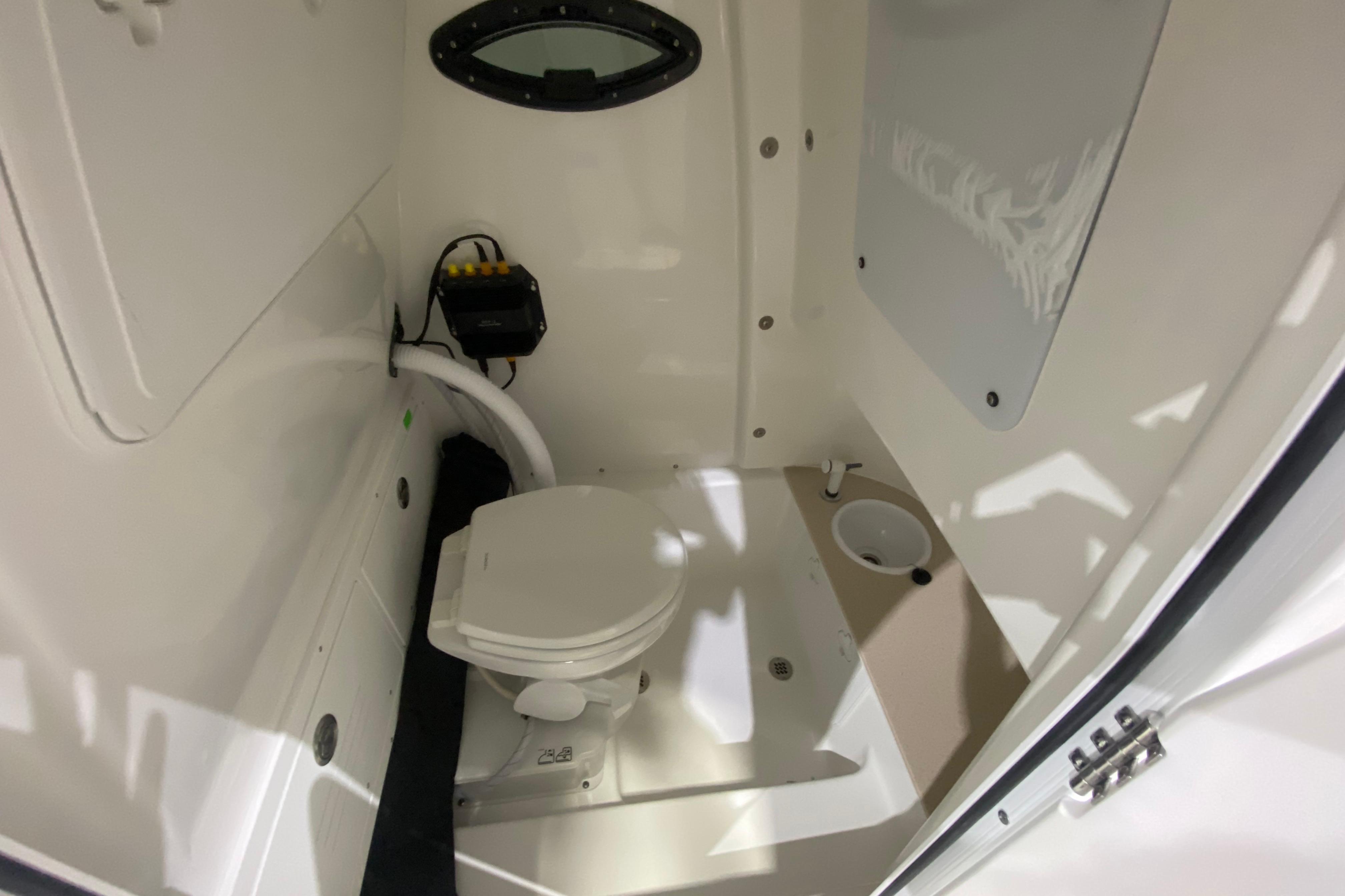 Interior of 2027 Sea Pro 245FLXR Sandbar boat featuring a compact marine toilet.