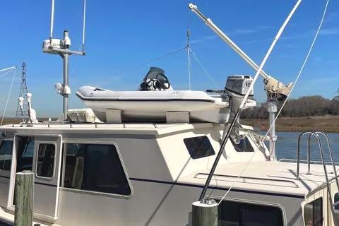 1997 Rosborough Trawler docked, featuring a small boat on the roof under a clear blue sky.