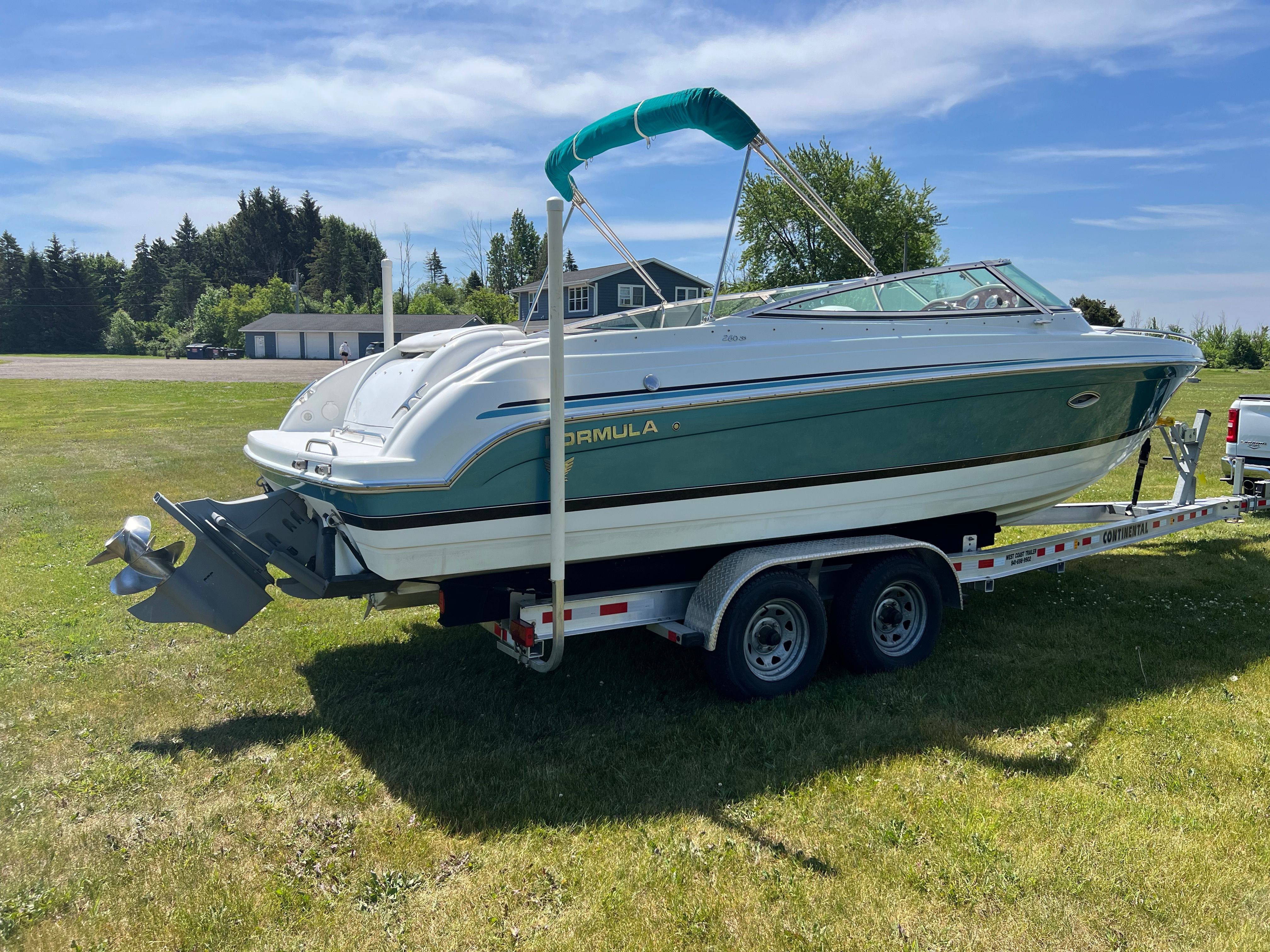 A 2005 Formula 260 Sun Sport on a trailer, featuring a green canopy and white hull.