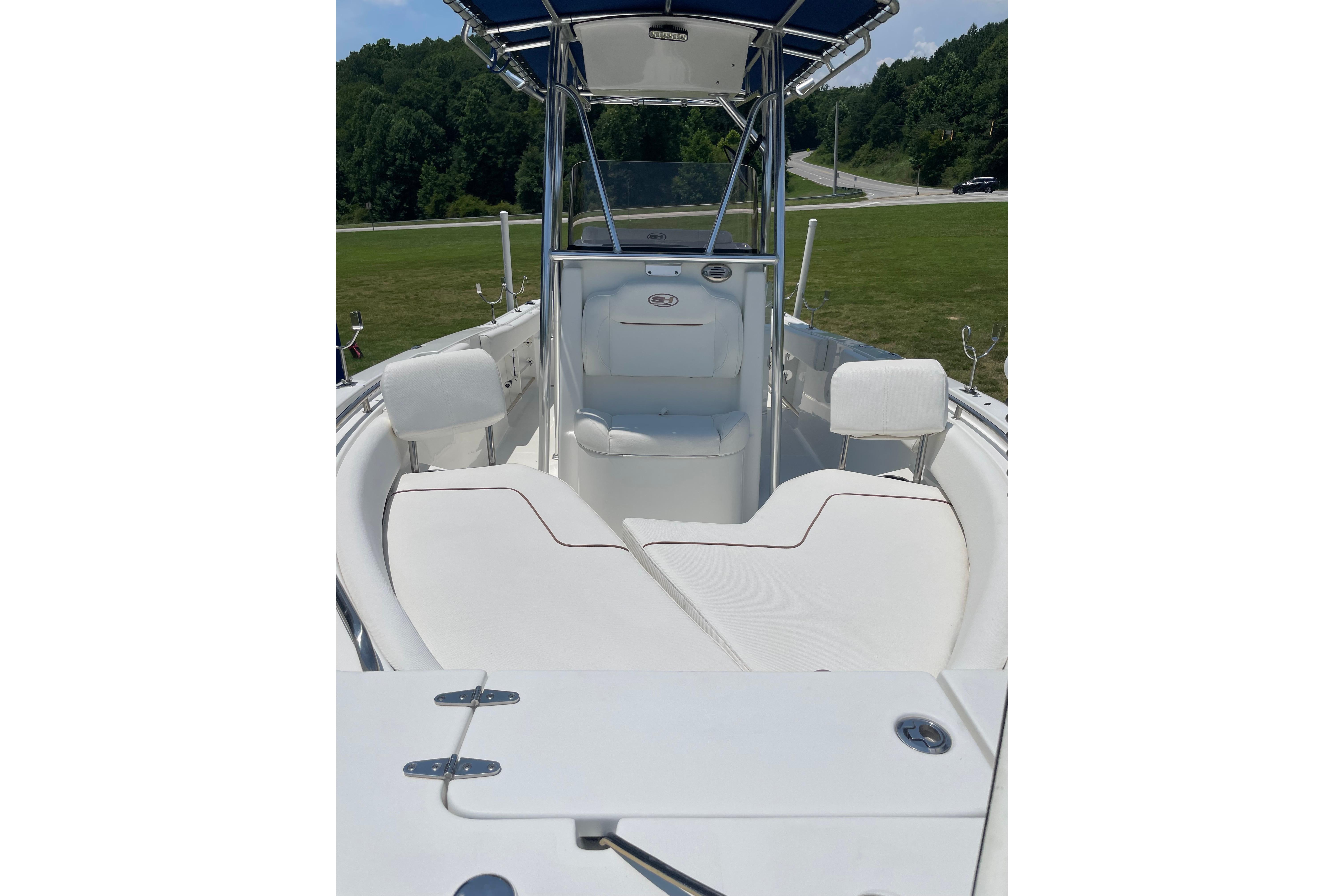 2018 Sea Hunt Ultra 234 boat interior with white seating and console, parked on grass.