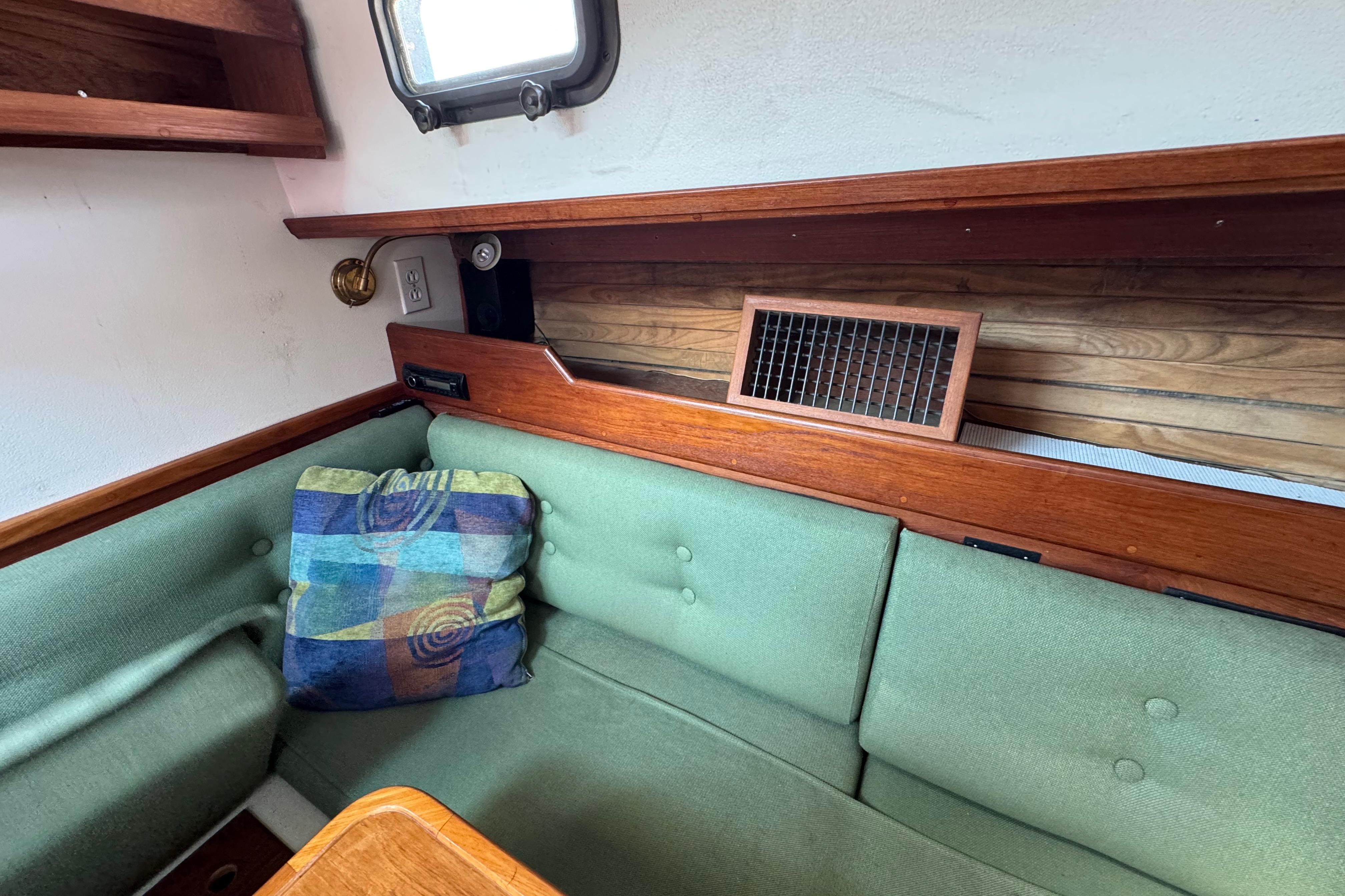 Interior of 1989 Cape Dory 30 Motorsailer with green cushions and colorful pillow.