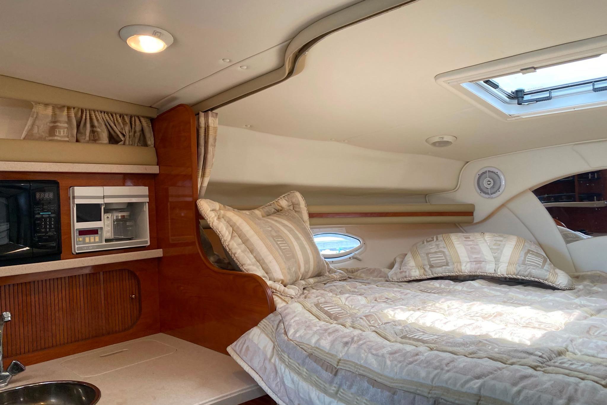 Interior cabin of 2003 Rinker Fiesta Vee 342 with bed and kitchenette.