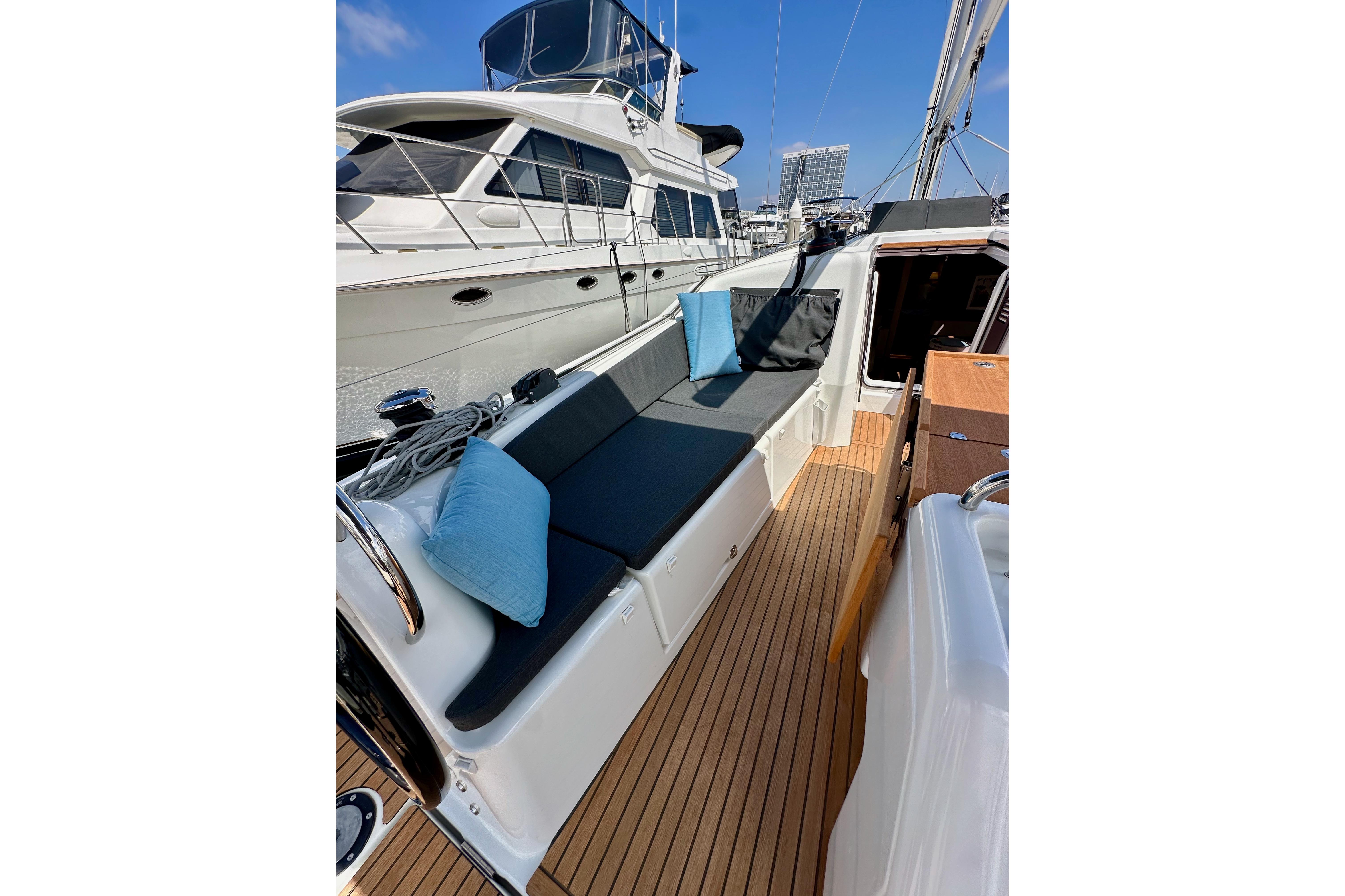 2024 Jeanneau Sun Odyssey 410 yacht deck with cushioned seating and wooden flooring.