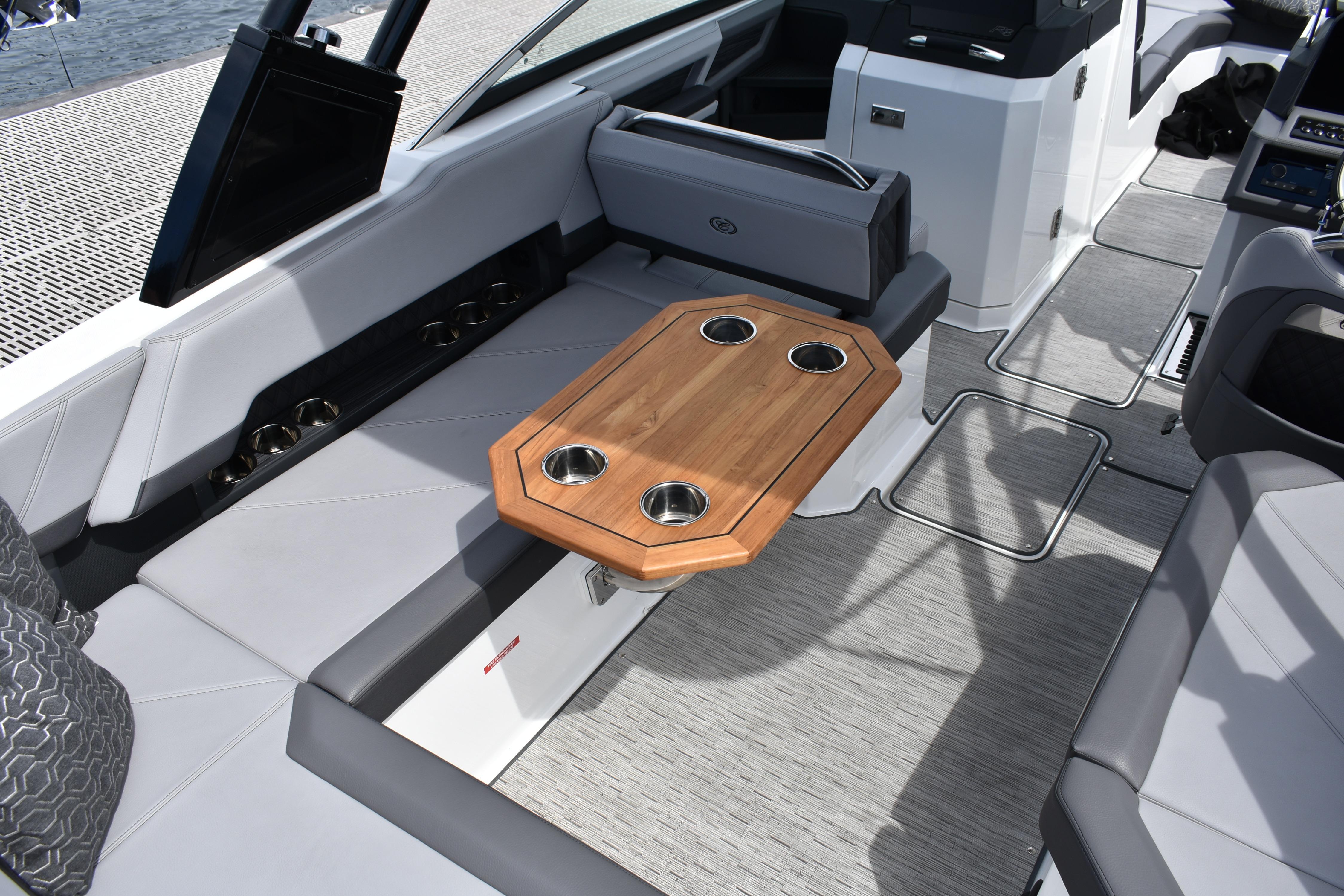 2023 Cobalt R8 boat interior with wooden table and cup holders, featuring sleek seating.