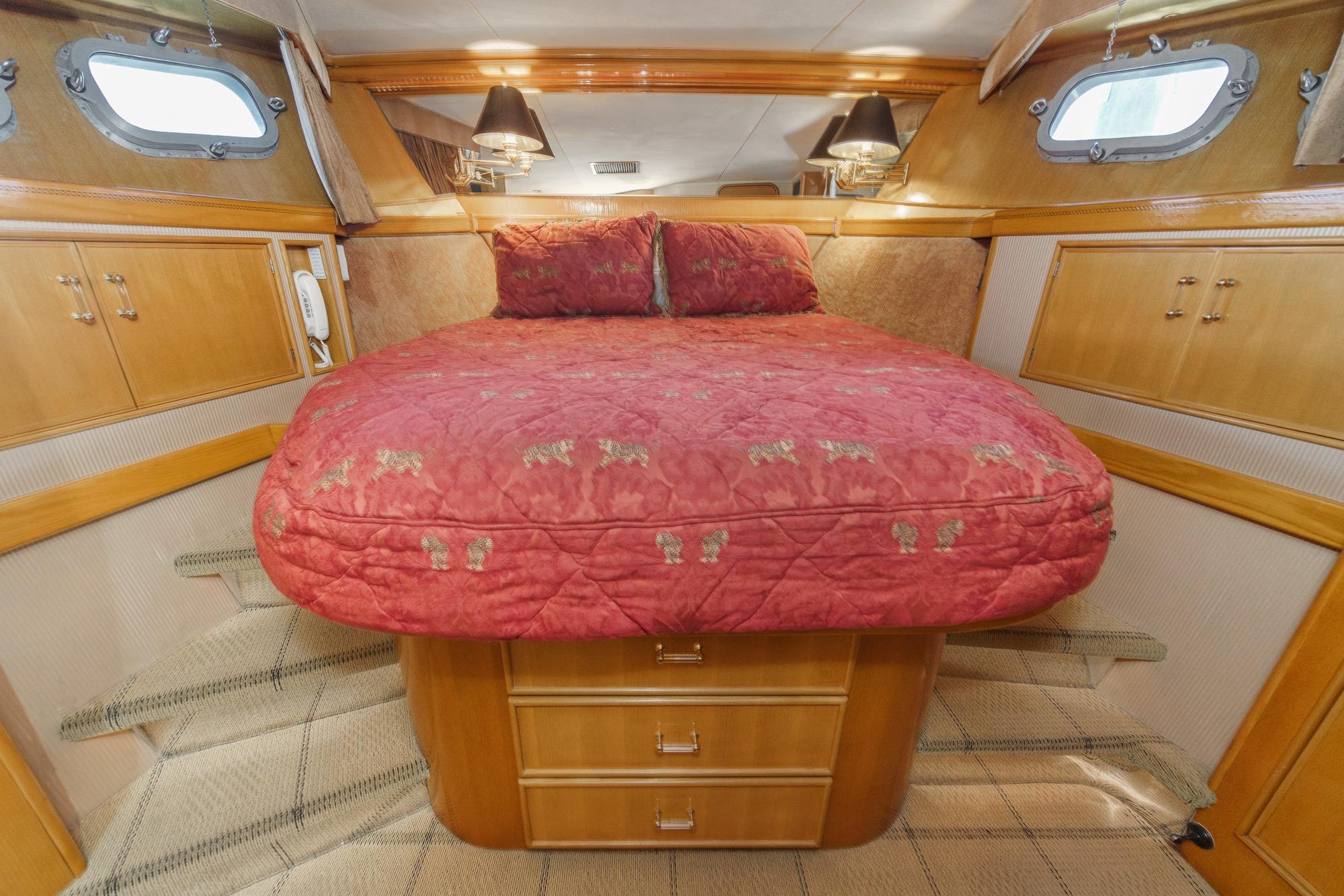 Cozy cabin interior of 1990 Seaton Long Range Cruiser with red bedding and wooden cabinetry.