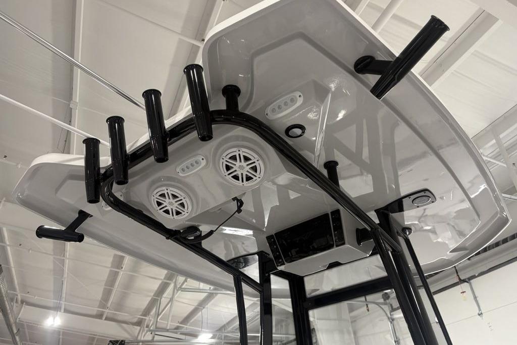 2026 Tidewater 2300 Carolina Bay boat T-top with rod holders and speakers in a showroom.