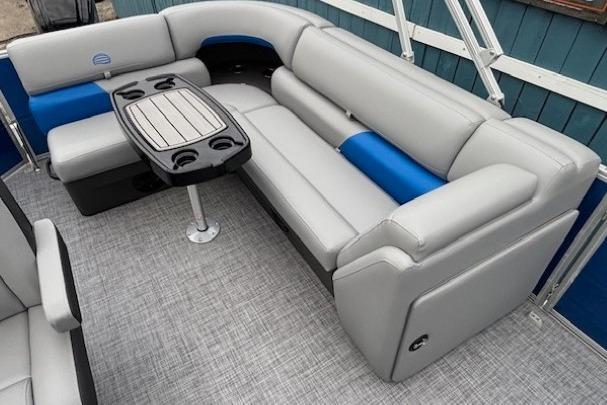 2026 Sun Tracker Party Barge 20 DLX interior with gray and blue seating, table, and cup holders.