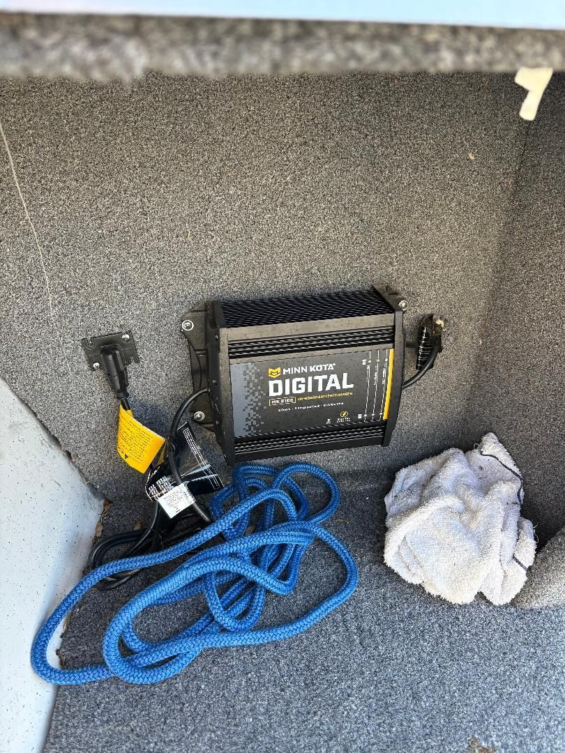 A Minn Kota digital charger in a boat with a blue rope and a towel.