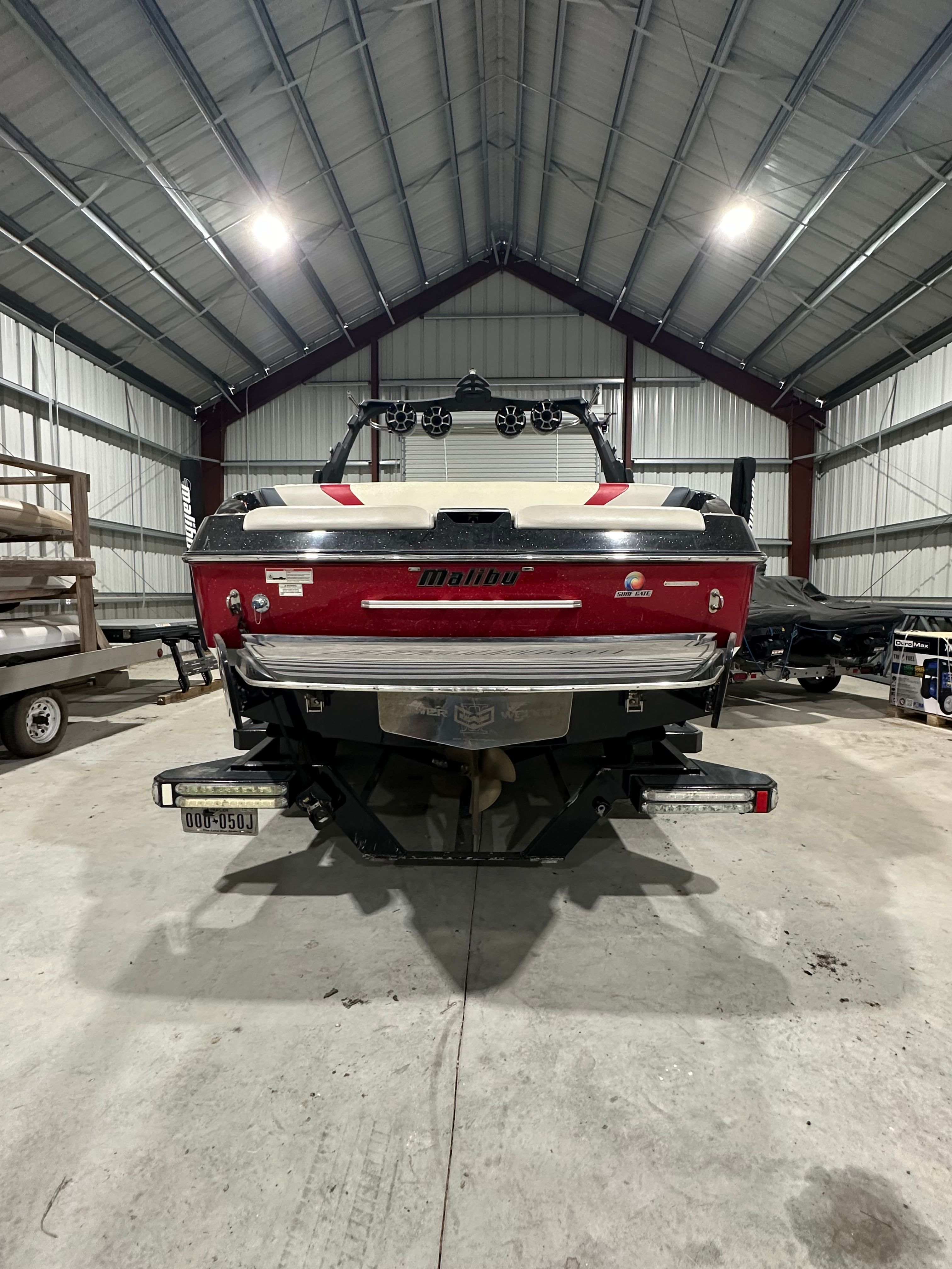 A red Malibu Wakesetter 24 MXZ boat is parked in a storage facility.