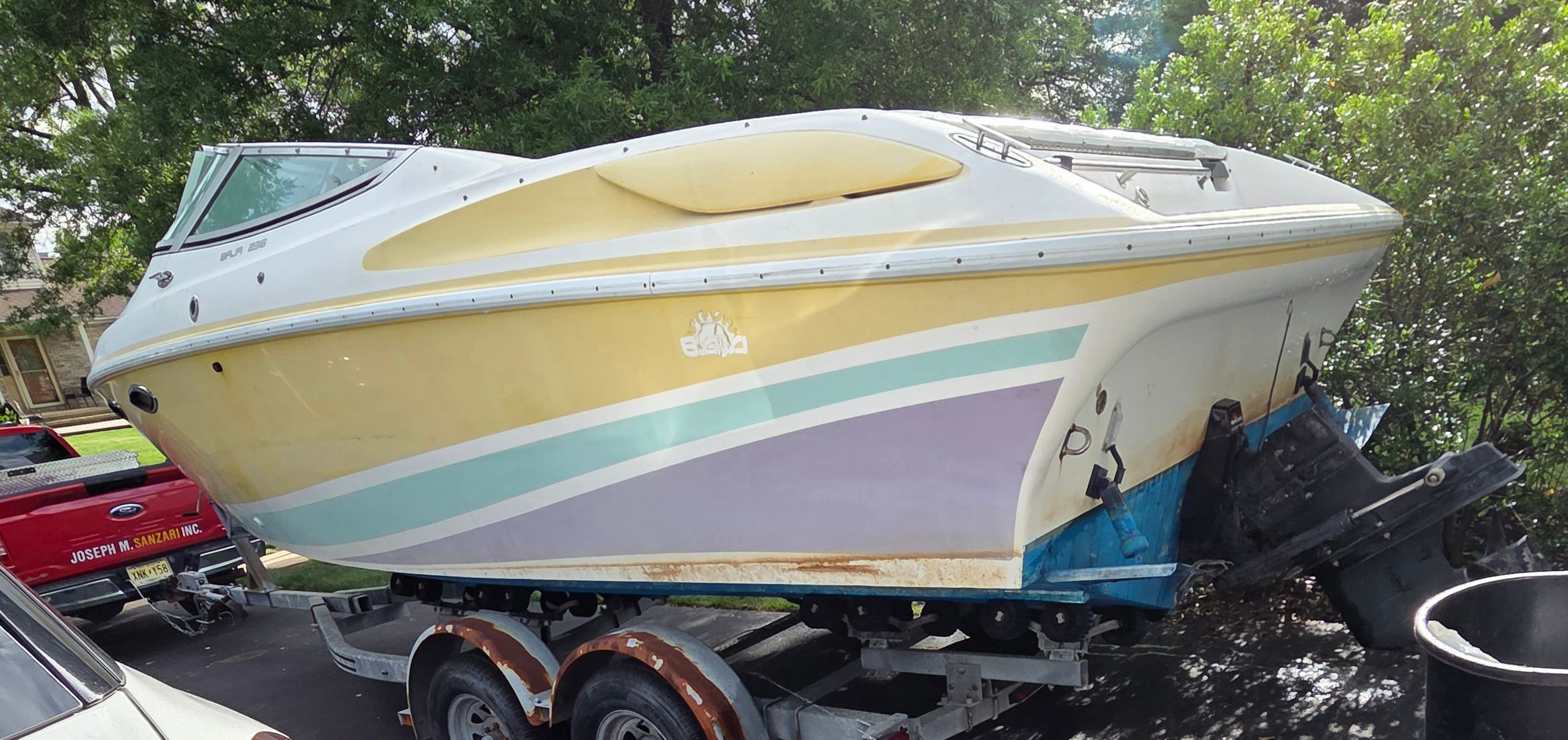 A 1993 Baja 238 boat on a trailer, featuring yellow and purple paint.