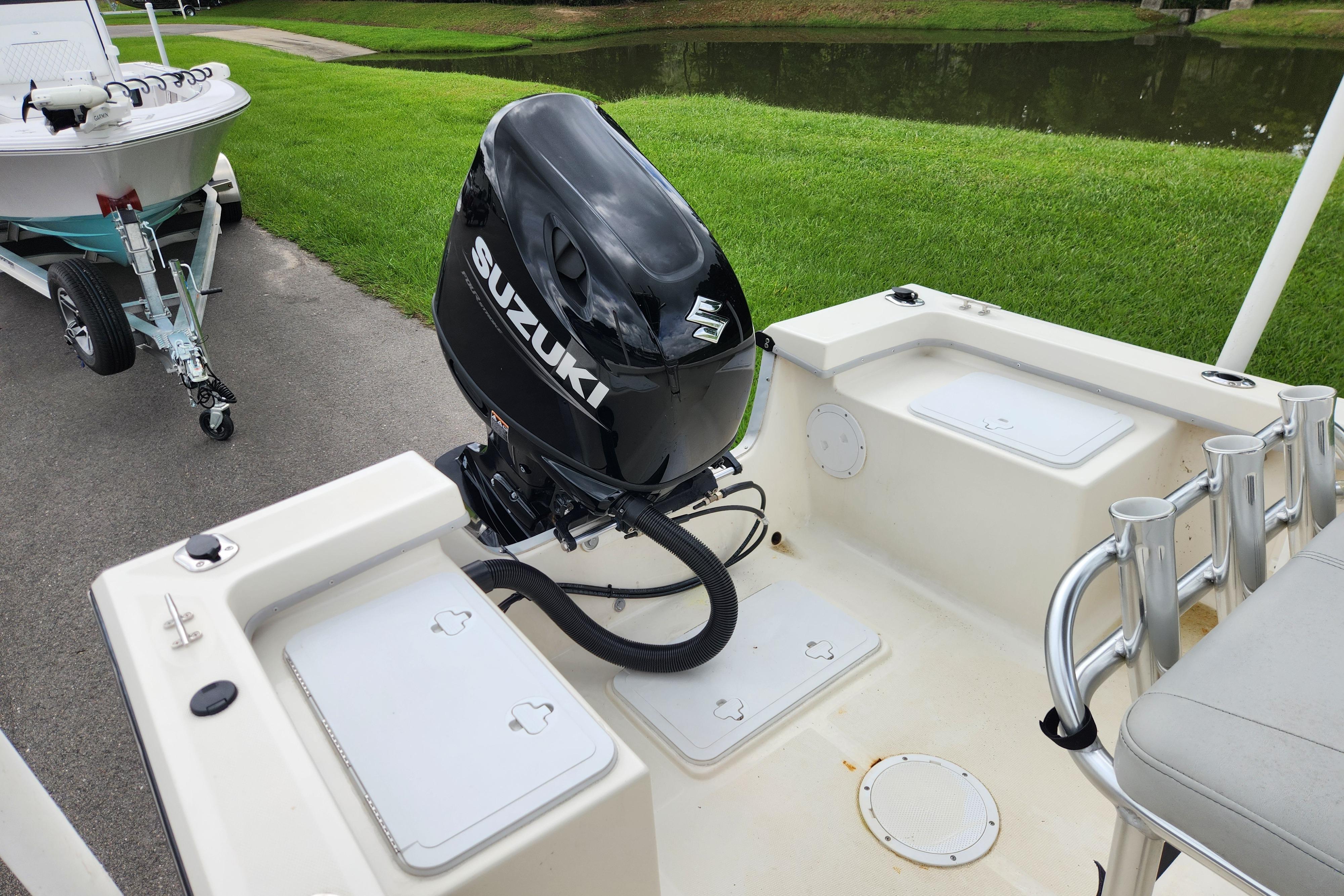 2023 May-Craft 1900CC boat with Suzuki outboard motor, parked near a grassy area.