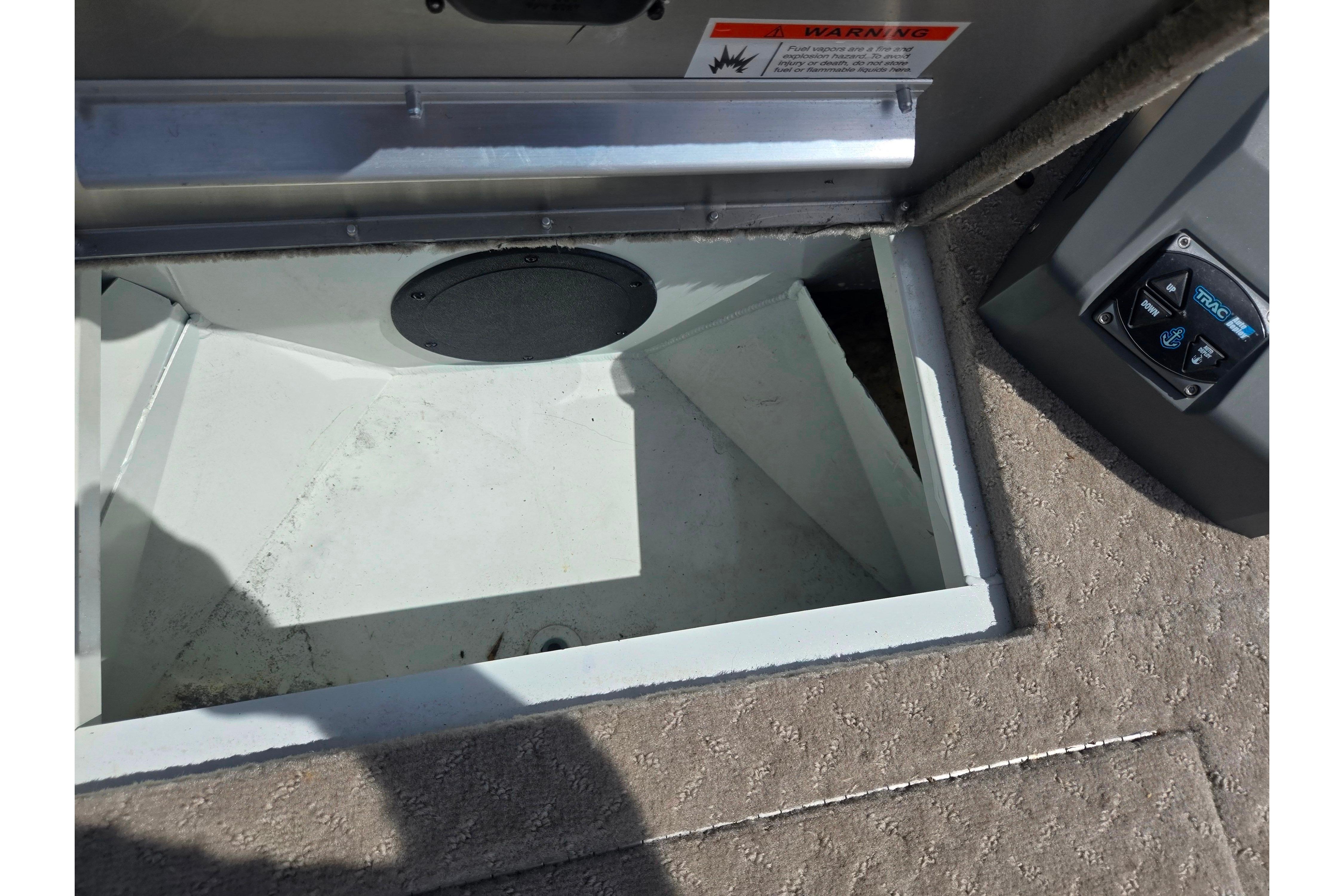 Open storage compartment on 2015 Lowe Sport Deck 224 boat, featuring carpeted flooring.