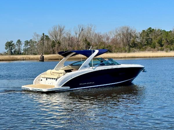 2018 Regal 3300 on calm water with a blue canopy and beige interior.
