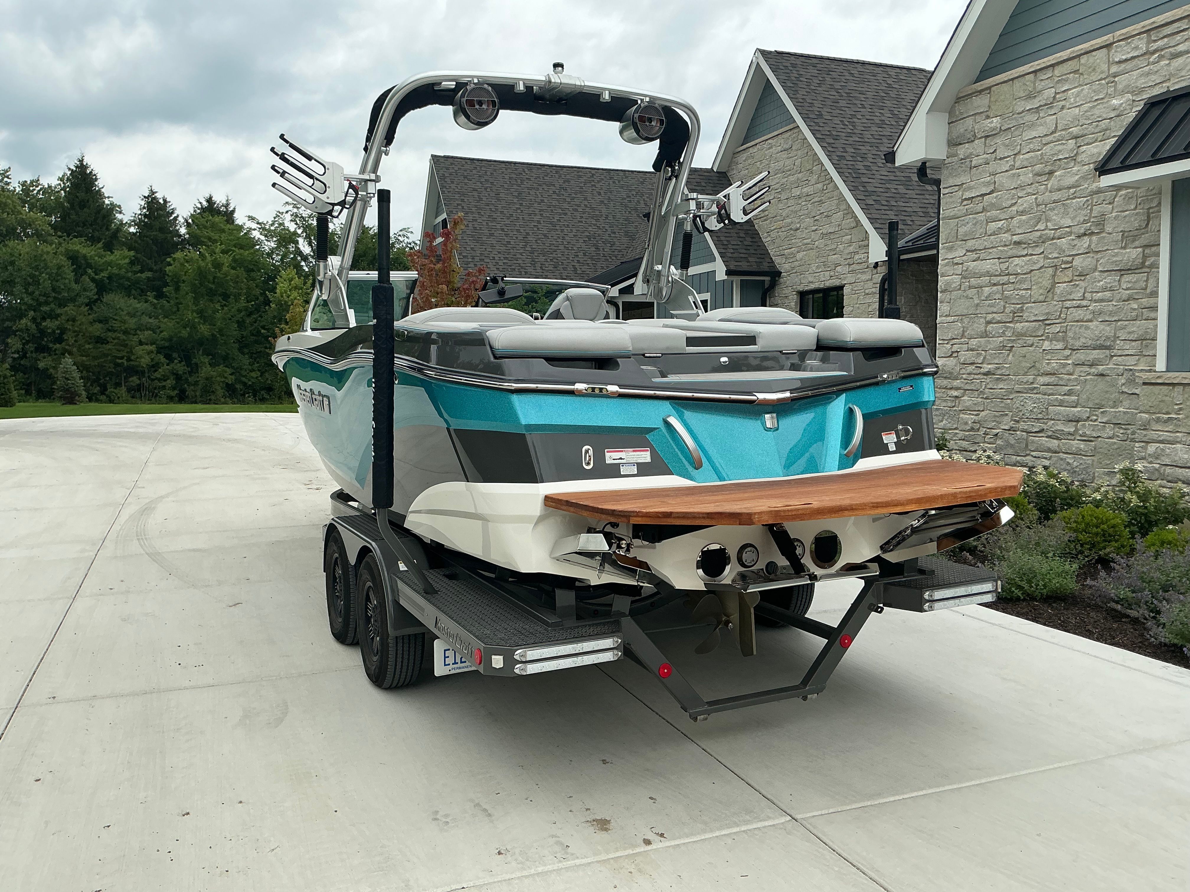 A turquoise 2019 MasterCraft XT22 on a trailer in front of a house.