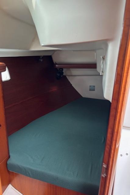 2001 Beneteau 361 cabin interior with green bedding and wooden accents.