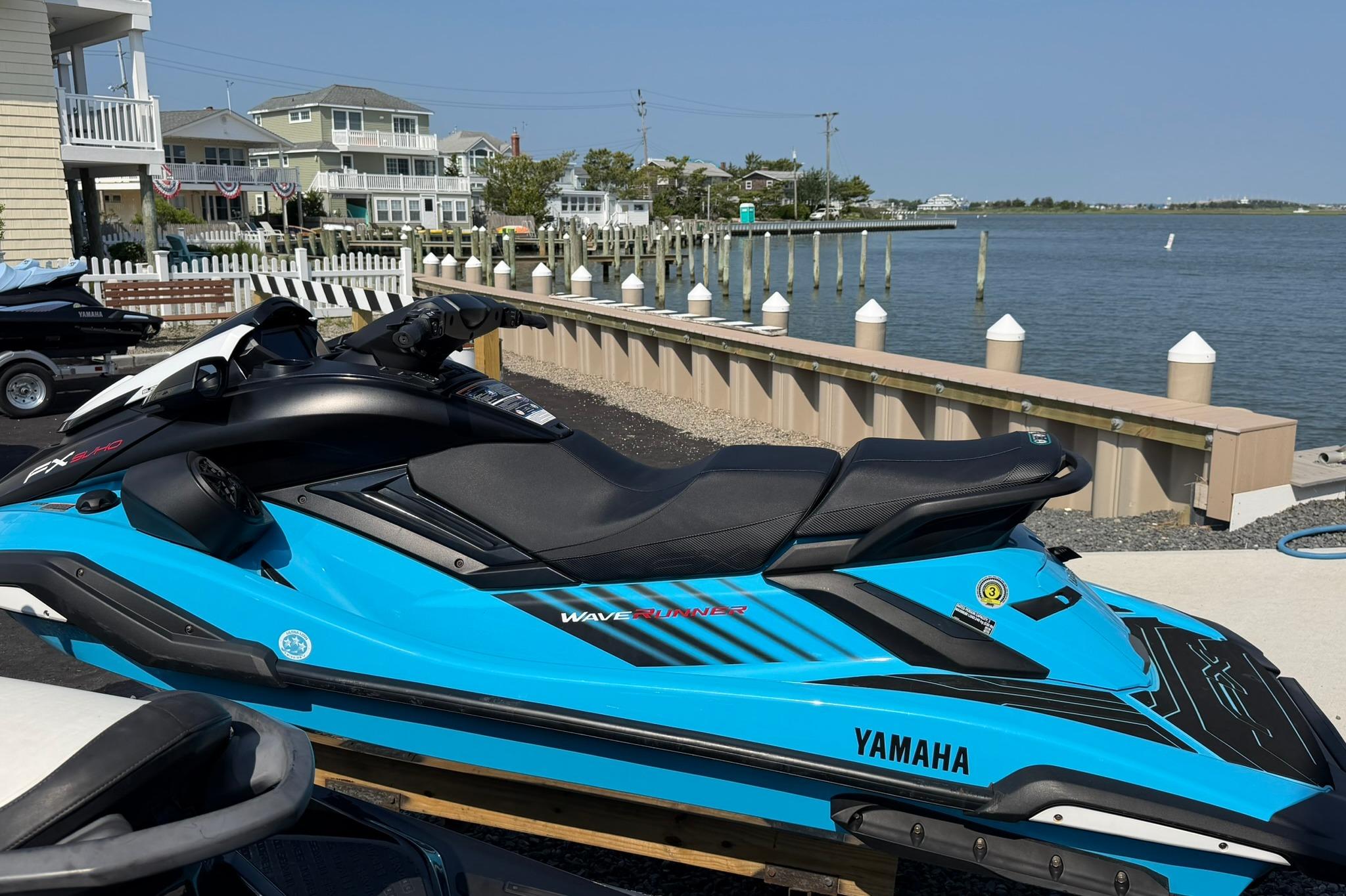 2025 Yamaha WaveRunner FX SVHO in vibrant blue, docked by a scenic waterfront.