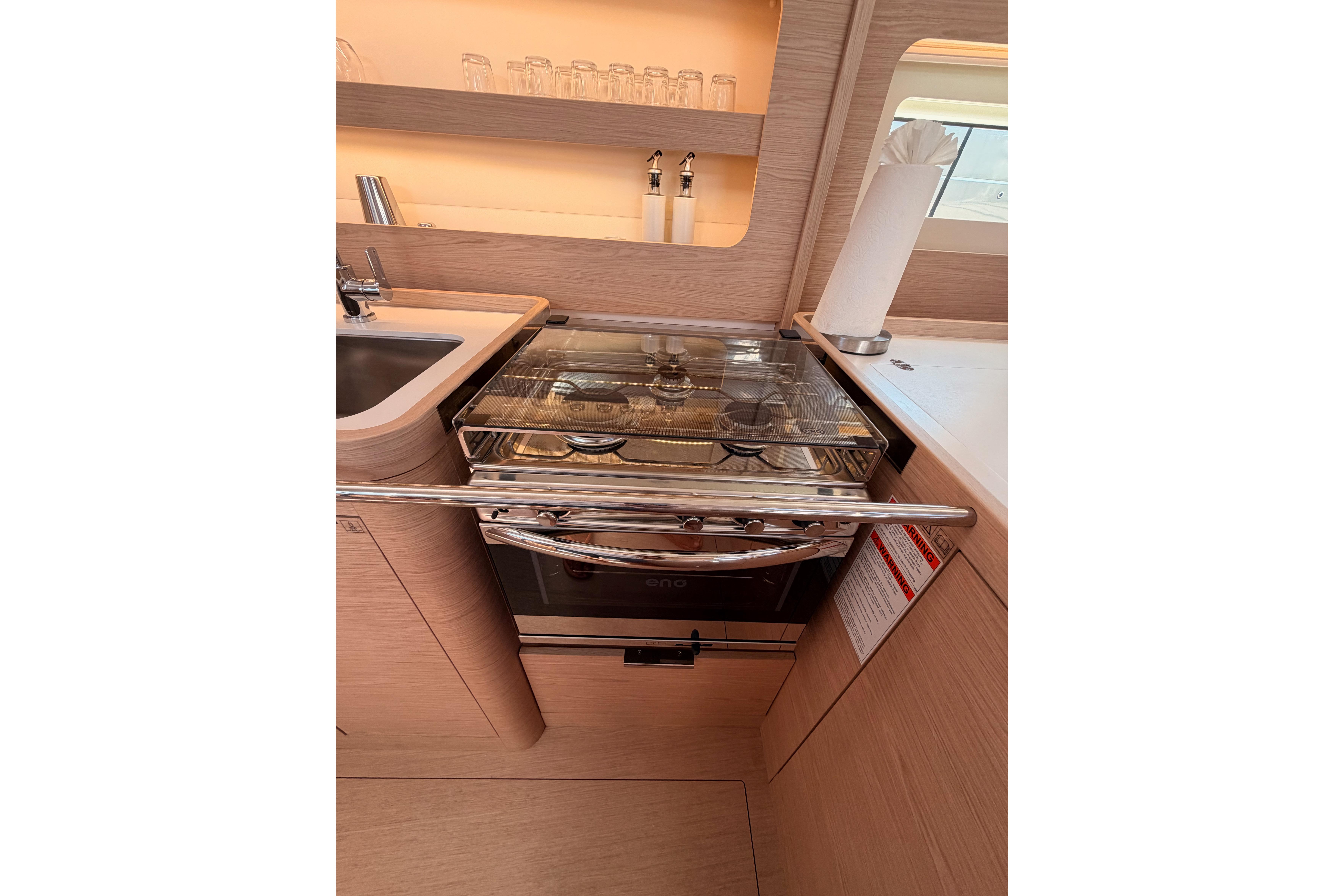 Modern kitchen in 2022 Beneteau Oceanis Yacht 54, featuring sleek appliances and elegant wood finish.