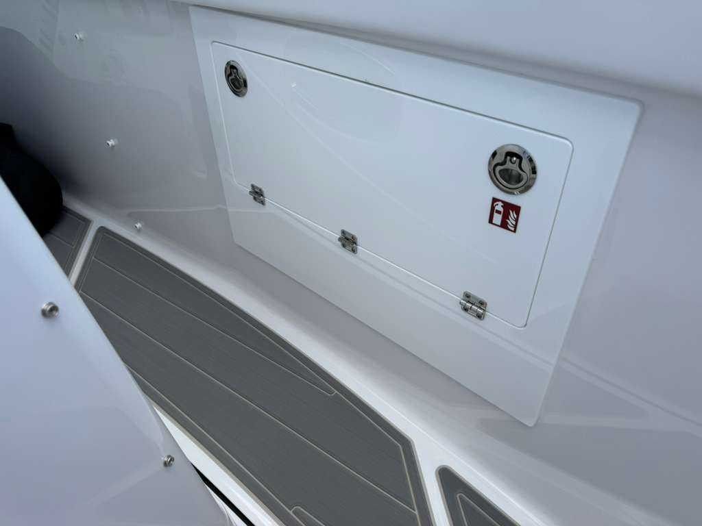 Interior view of a boat with gray flooring and white storage compartment.