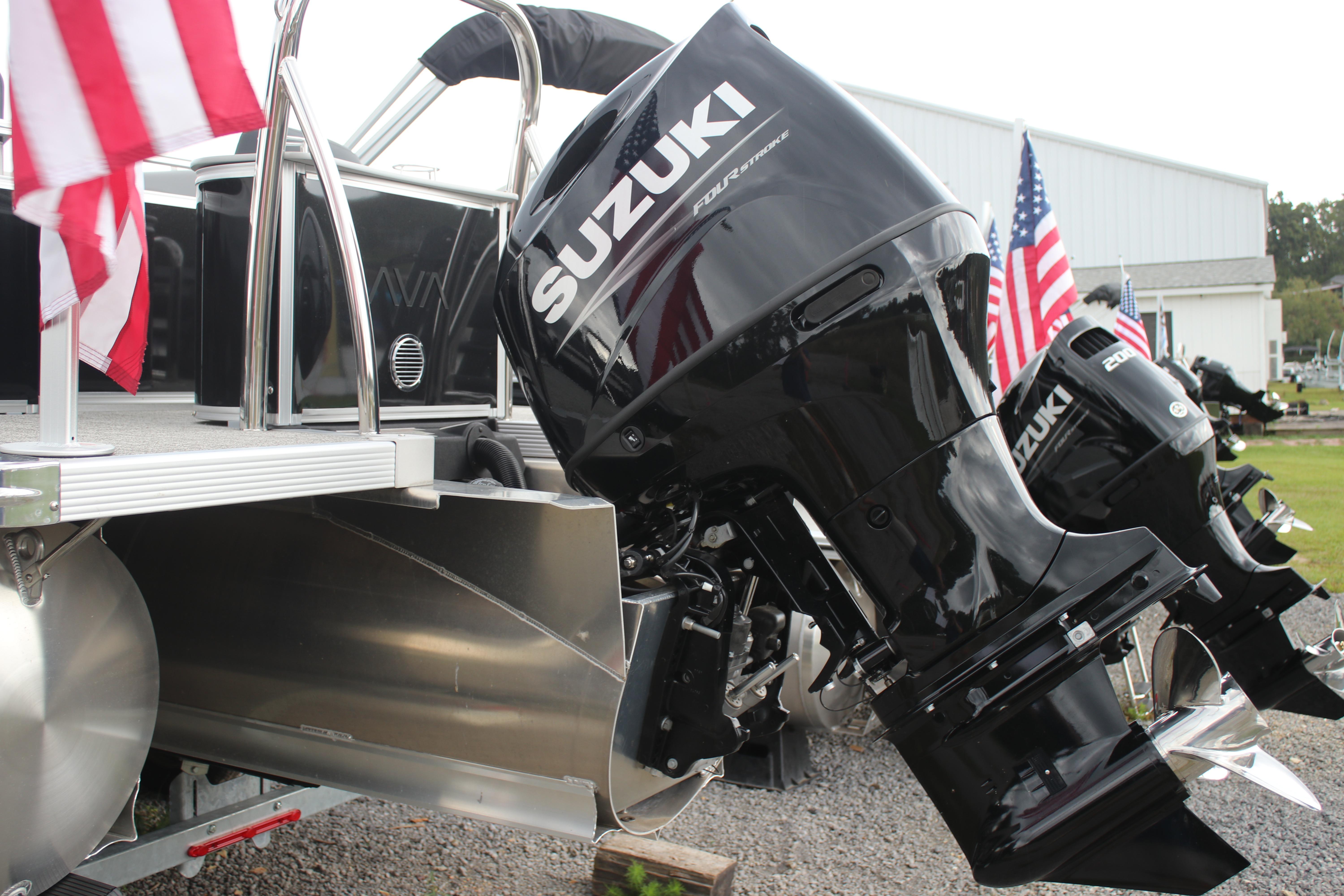 2025 Avalon LSZ Quad Lounger with Suzuki outboard motors and American flags displayed.