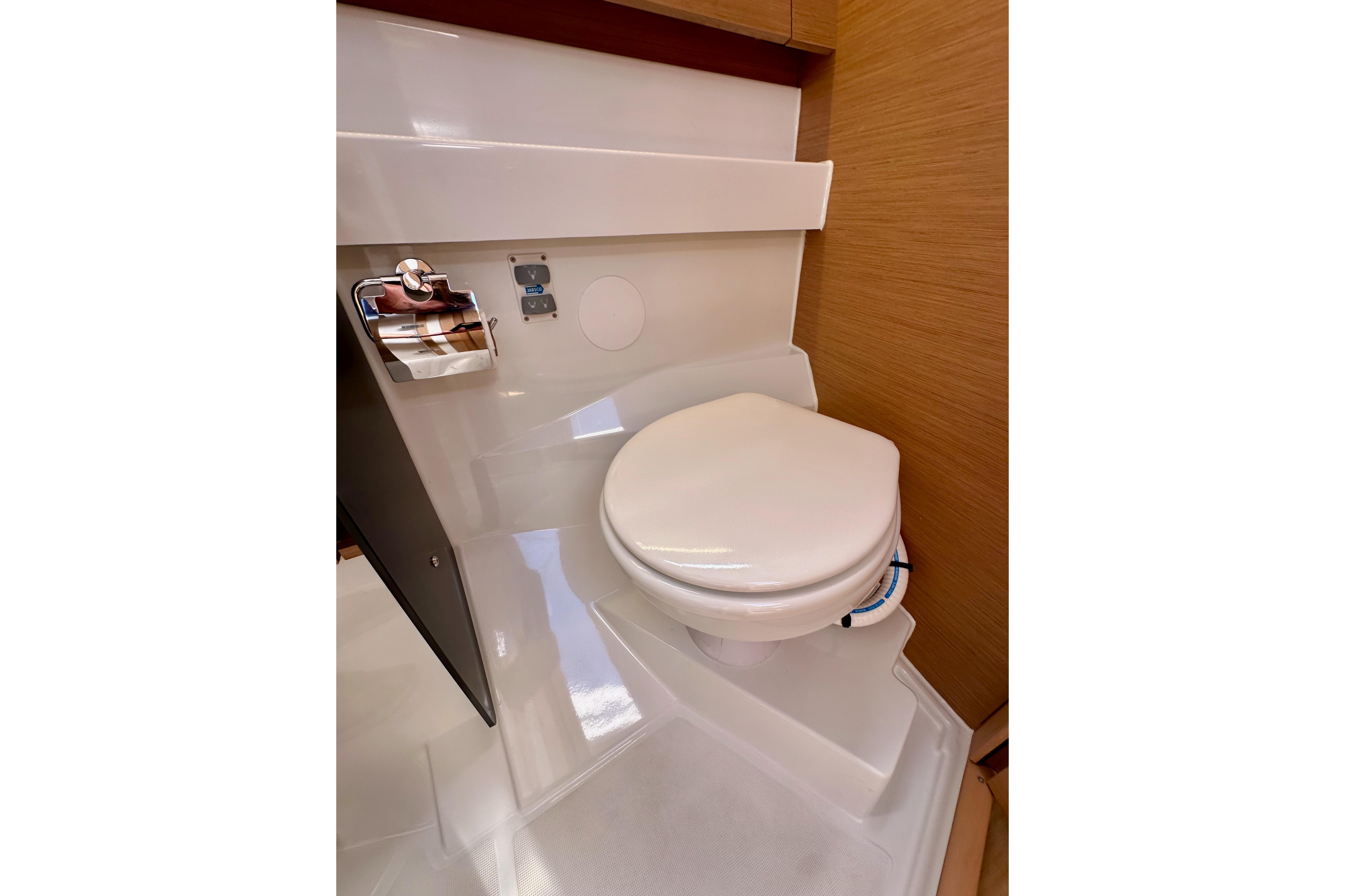 2024 Jeanneau Sun Odyssey 410 yacht bathroom with modern toilet and wooden accents.