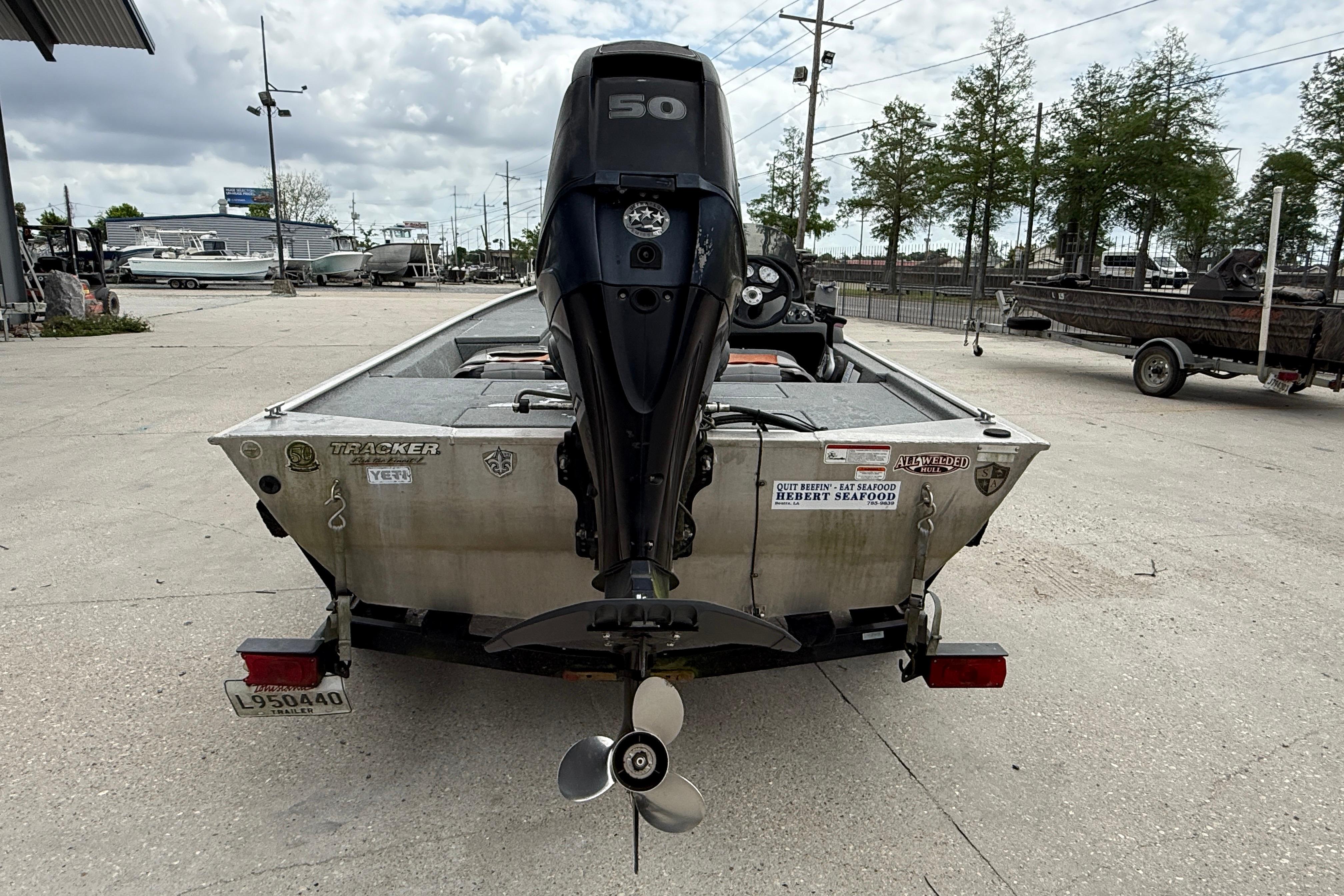 2016 Tracker Pro 170 boat with outboard motor, parked on a trailer in a marina.