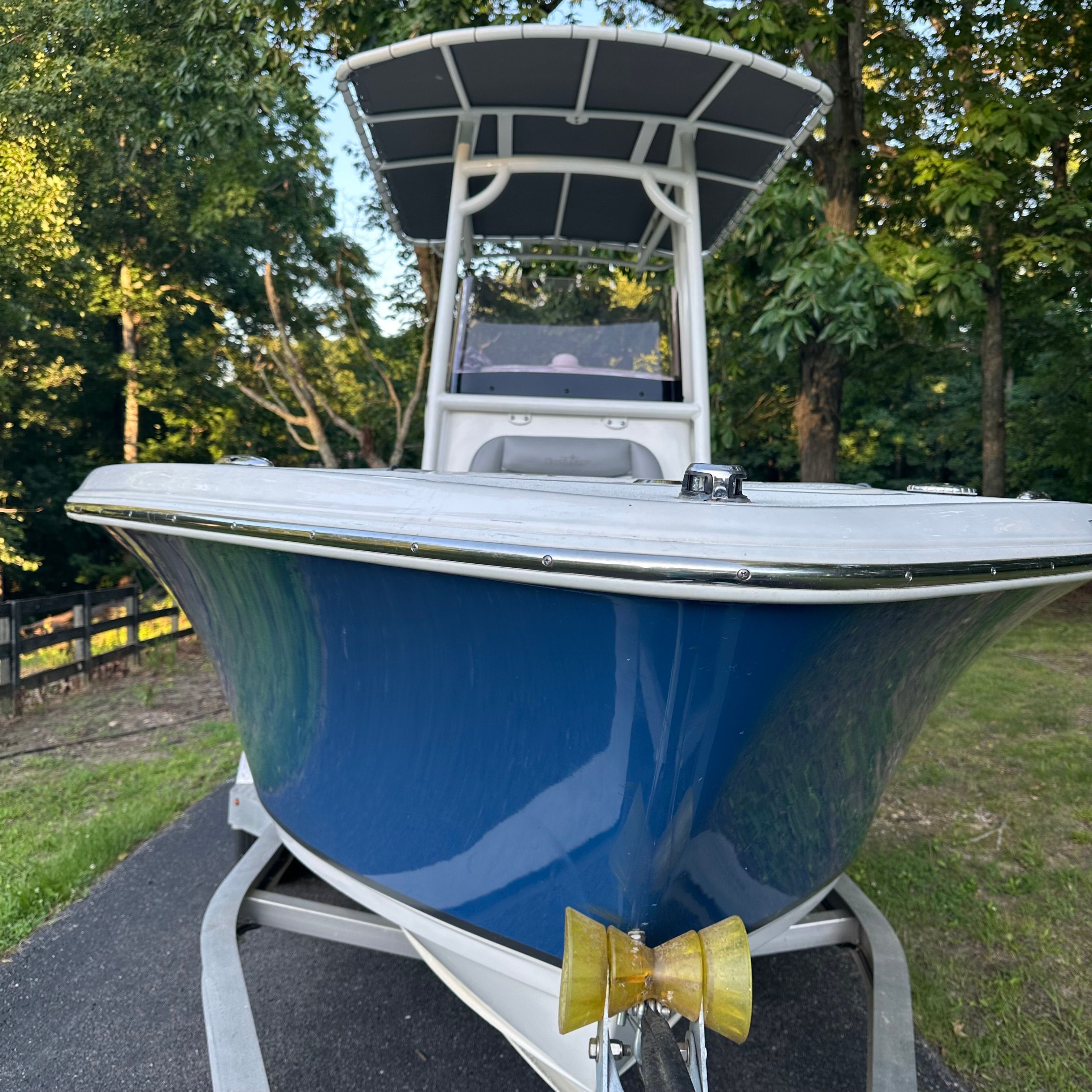 A blue boat on a trailer, surrounded by trees.