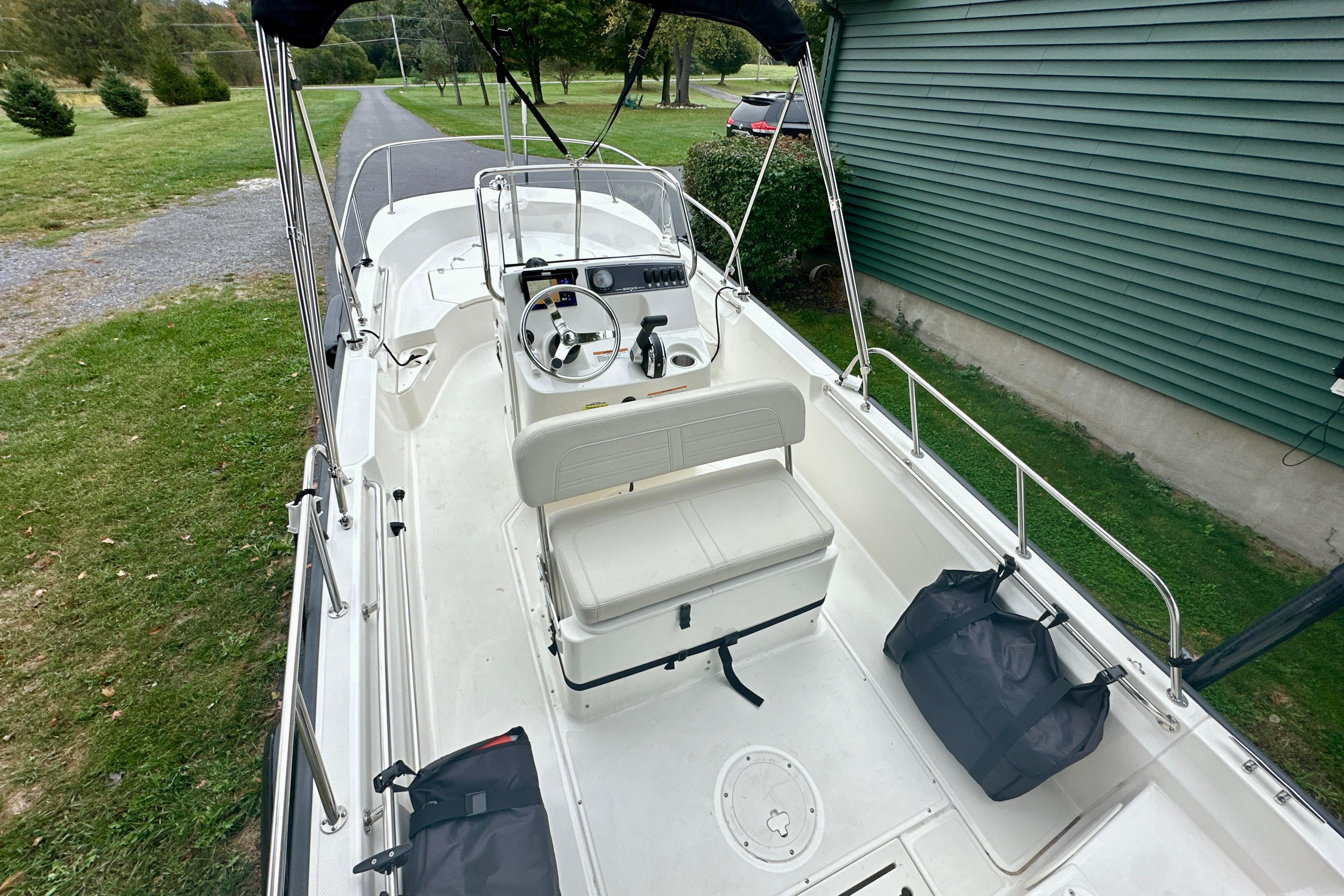 2024 Boston Whaler 170 Montauk boat interior with steering console and seating, parked on grass.
