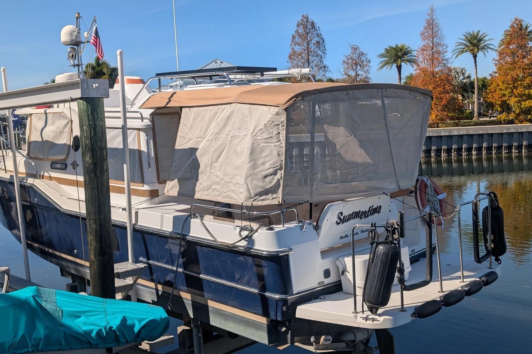 2015 Ranger Tugs R-29 S boat docked, covered, with scenic background.