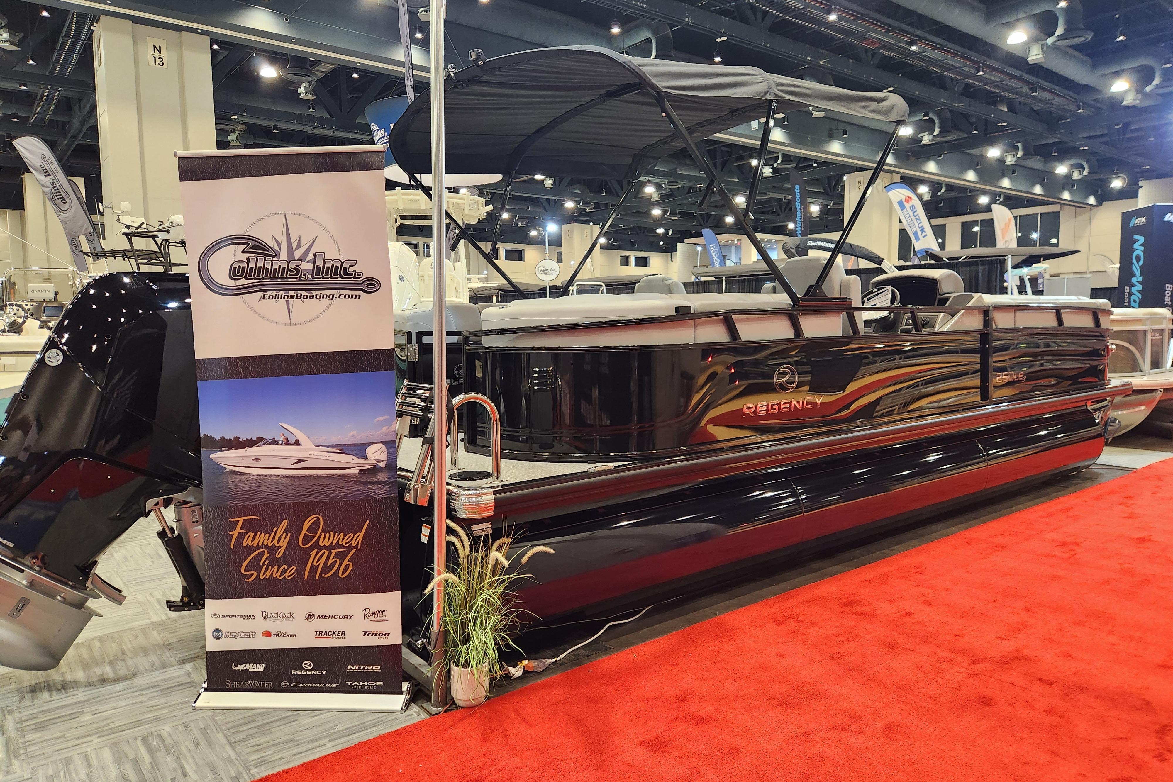 2025 Regency 250 LE3 boat displayed at a boat show with promotional banner.