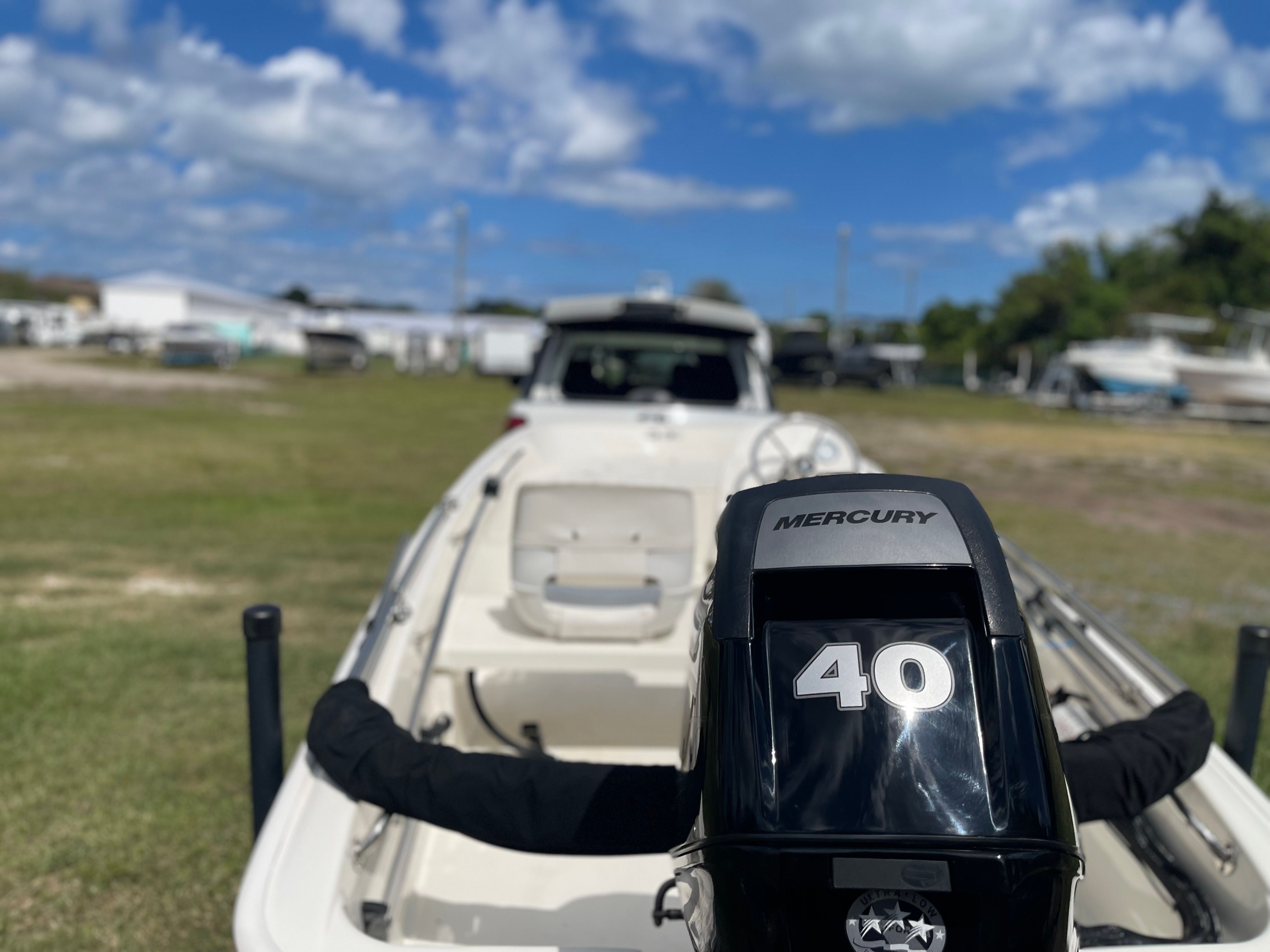 A 2017 Boston Whaler 130 Super Sport with a 40 HP Mercury engine, parked on grass.