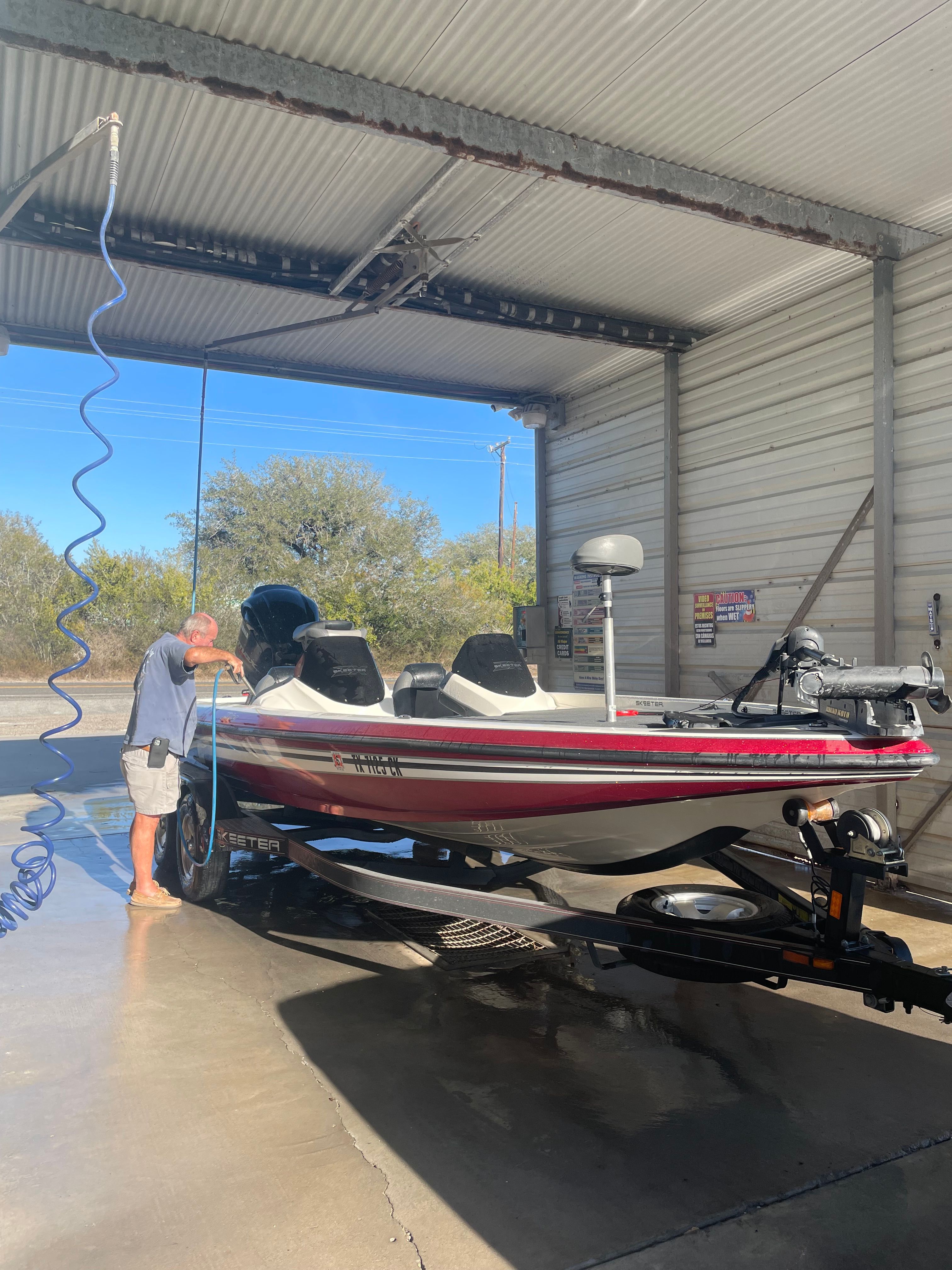 Man cleaning 2012 Skeeter ZX20 boat in wash bay.