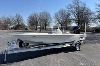 2026 Mako 18 Pro Skiff boat on trailer in parking lot, surrounded by trees.