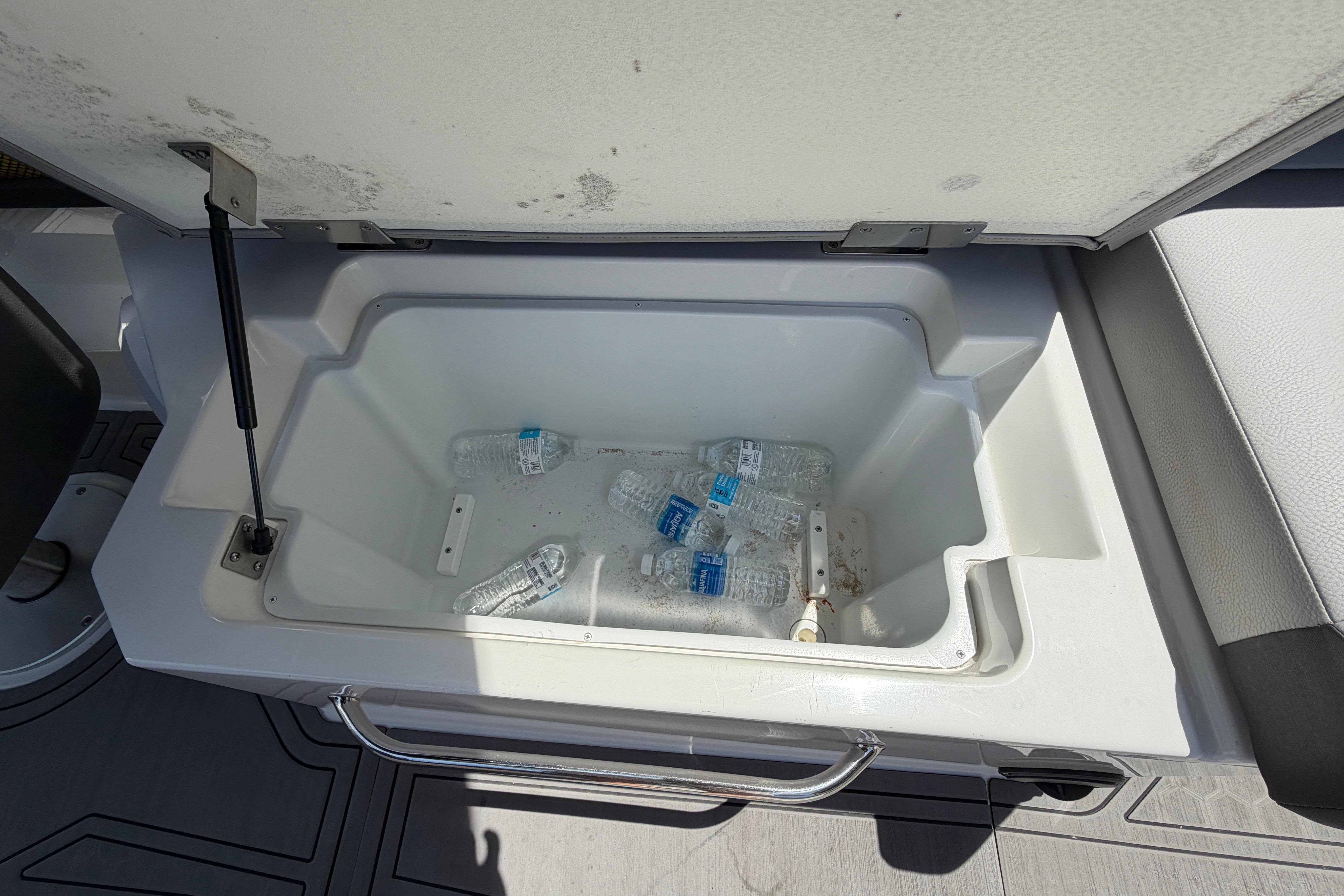An open cooler compartment with several water bottles inside.