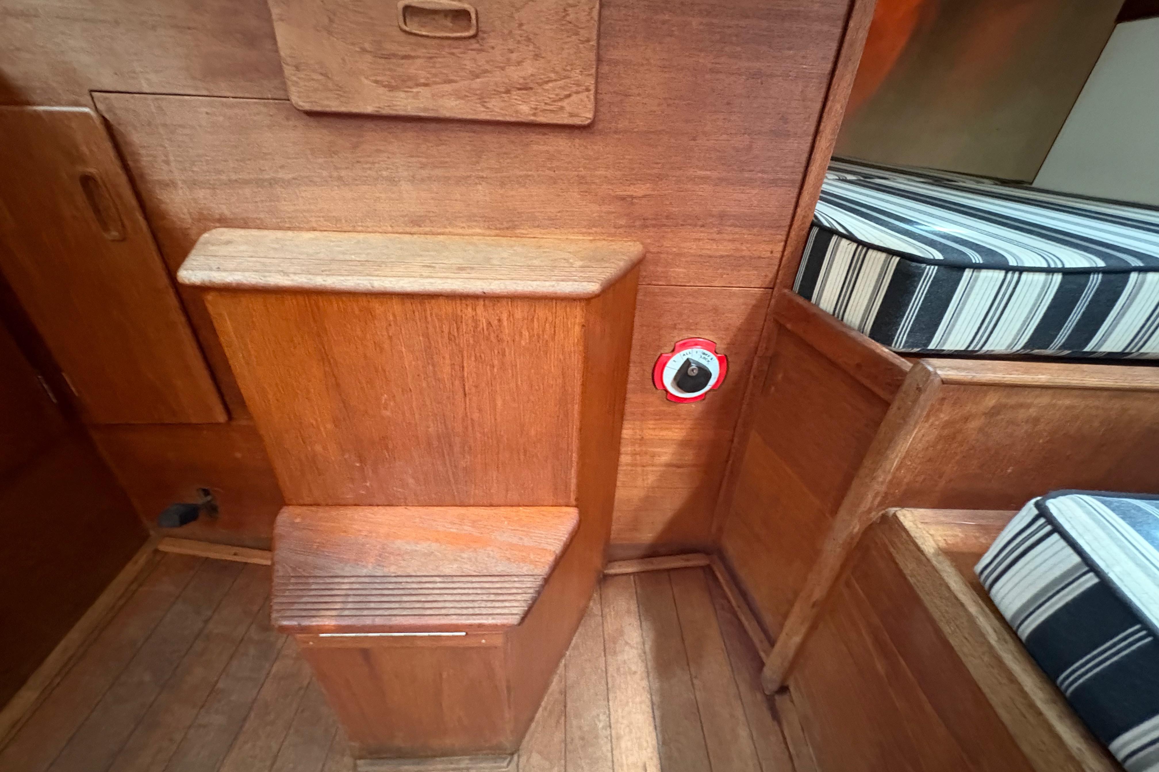 Interior of 1981 Sabre 31 sailboat with wooden cabinetry and striped cushions.