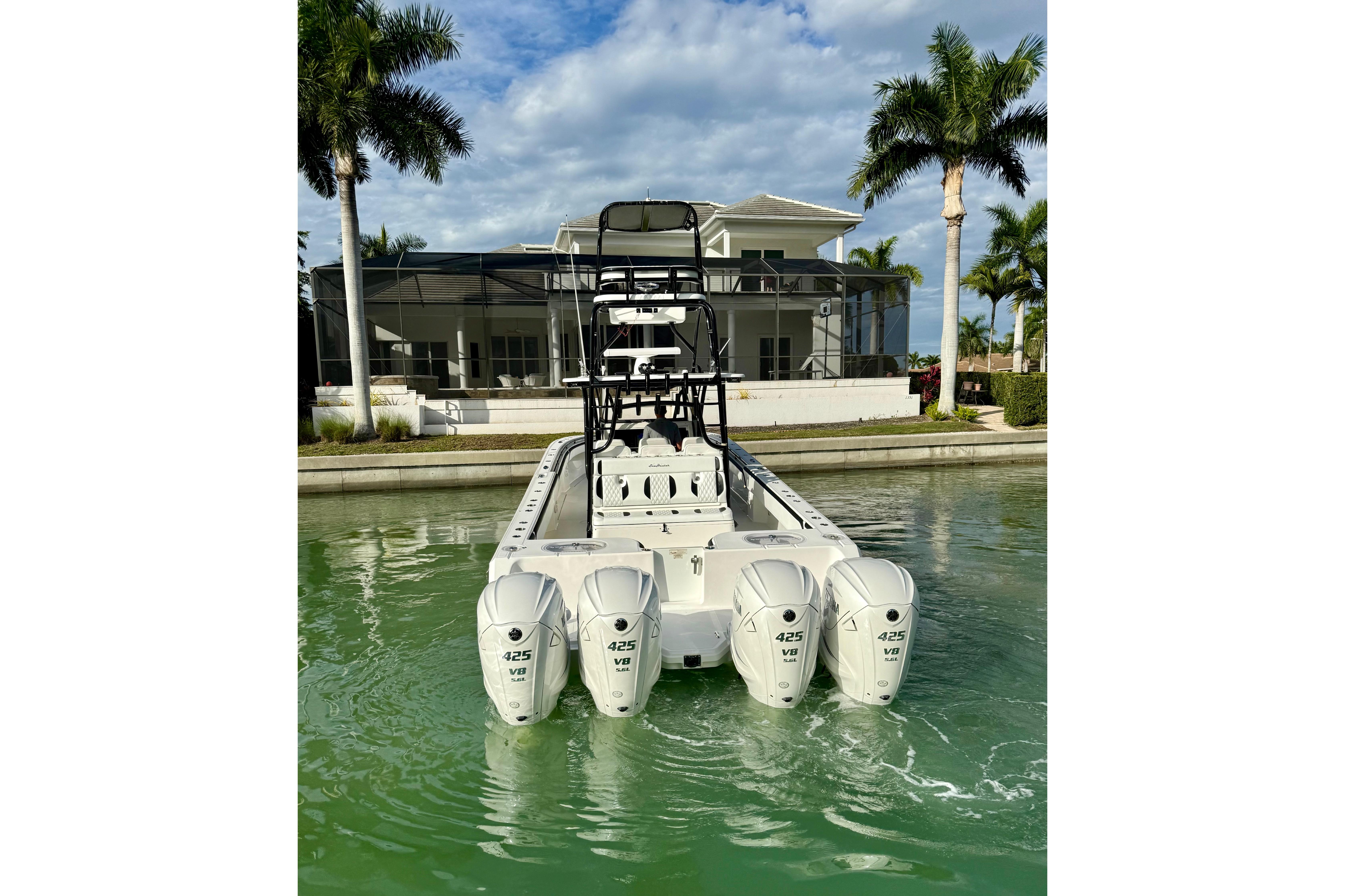 2020 SeaHunter 41 CTS boat with four powerful engines docked near a modern house.