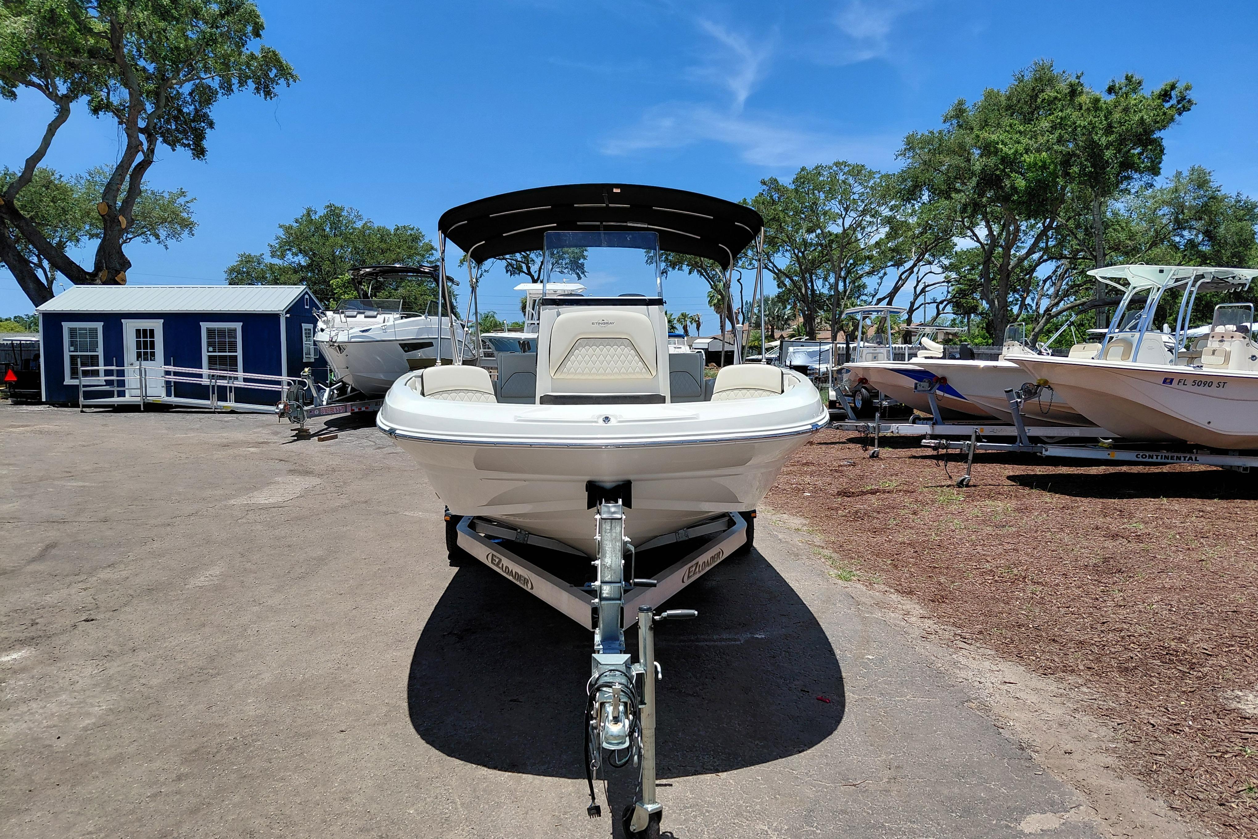 2023 Stingray 206 CC boat on trailer, parked outdoors under clear blue sky.
