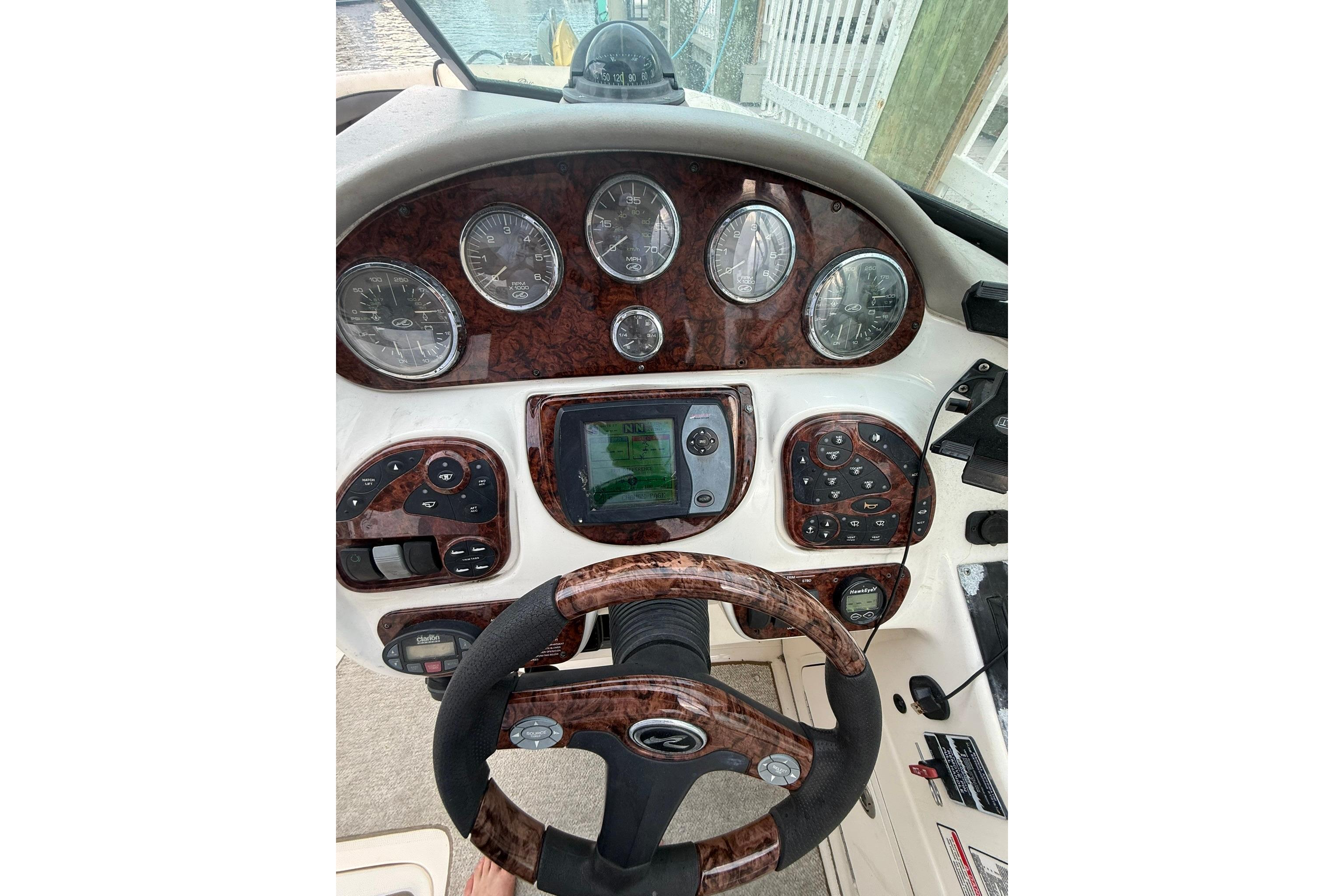 Dashboard of a 2005 Sea Ray 290 SLX boat with wood grain finish and gauges.